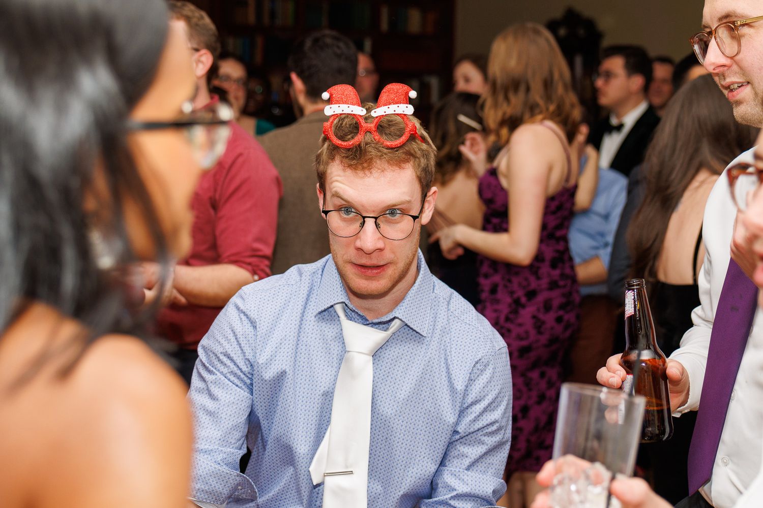 A couple sits at a table during a wedding reception, engaged in conversation with other guests.