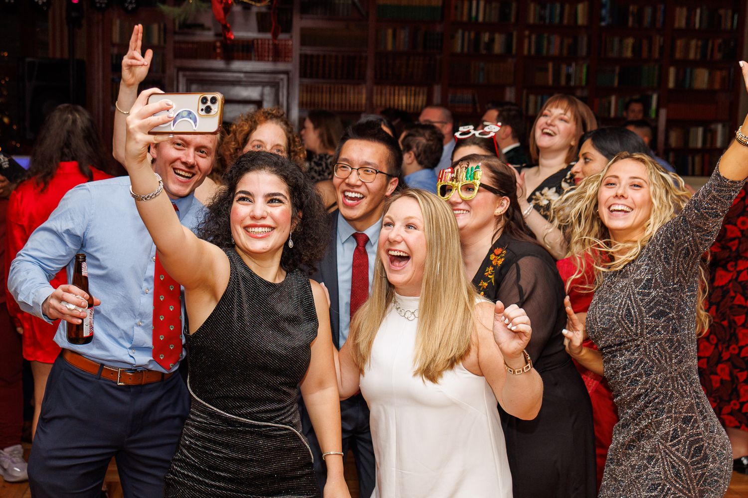 A group of people dancing and celebrating at a lively party with dark interior lighting and festive atmosphere.