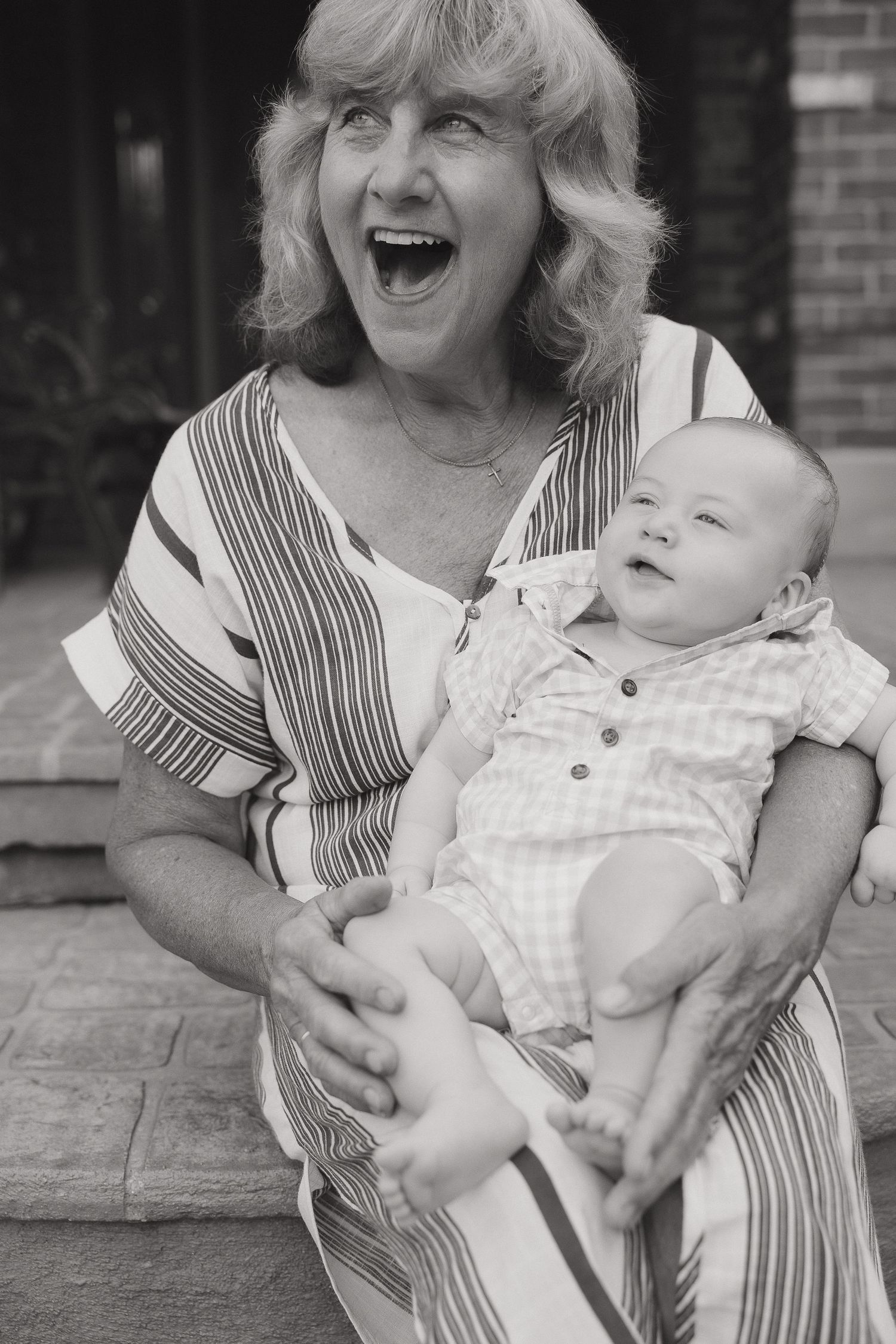 Black and white portrait of grandmother and baby sharing joyful moments together.