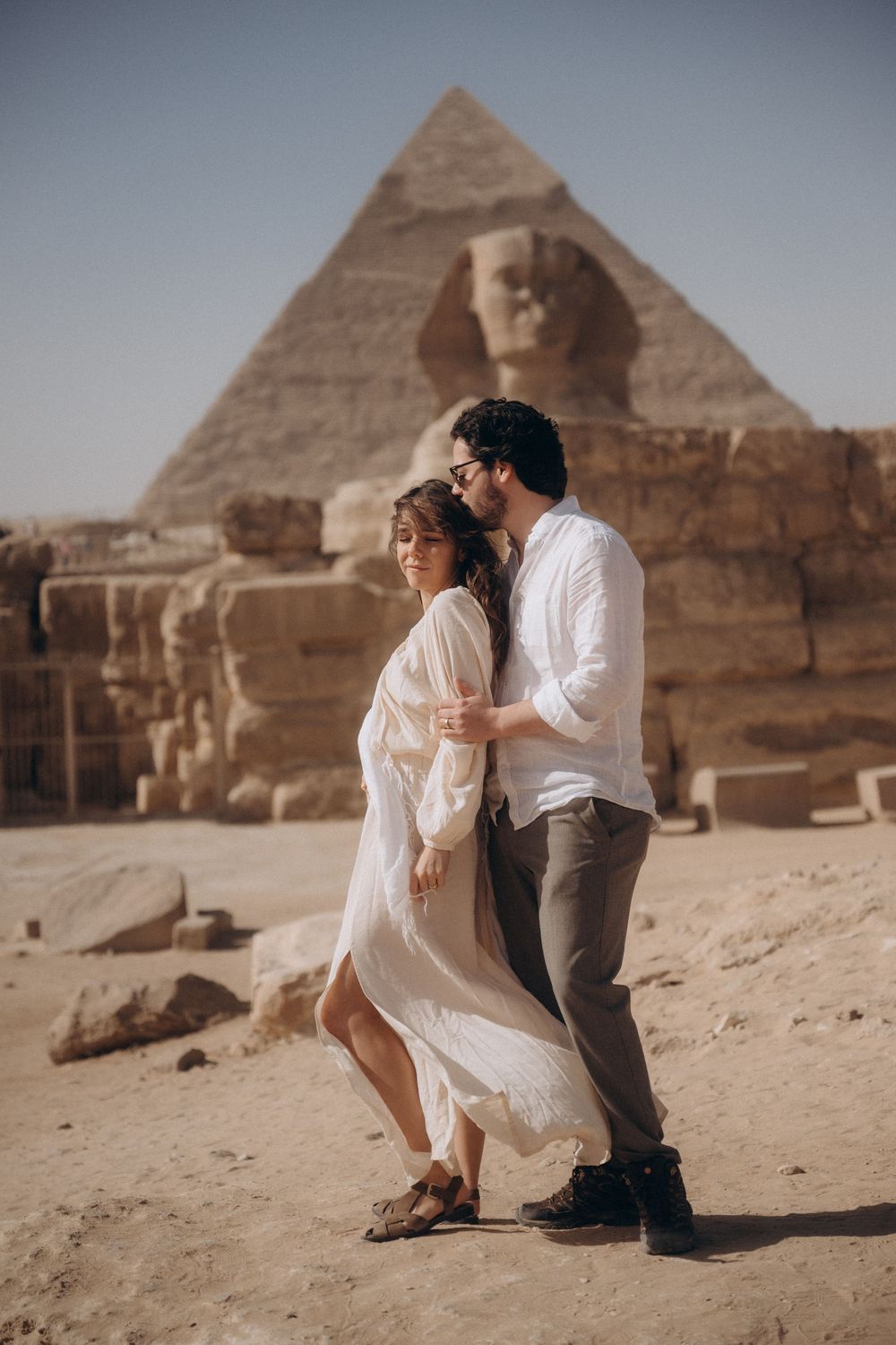 Romantic couple poses in front of the Great Pyramids of Giza in Egypt during a desert photoshoot.