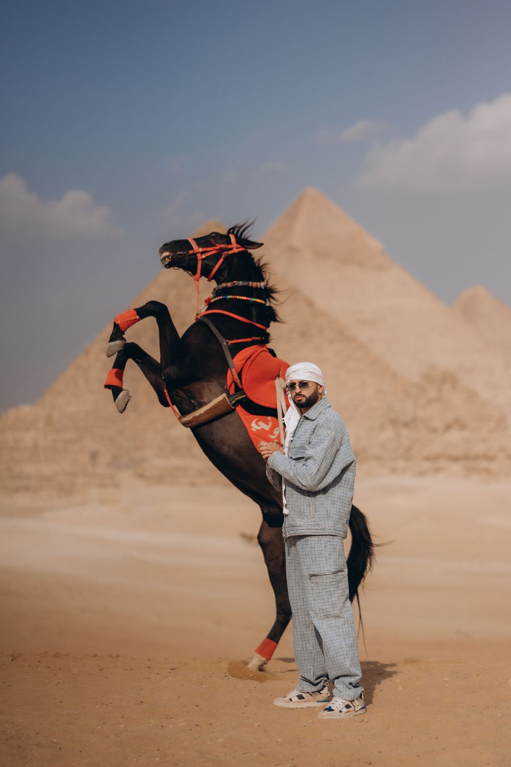 A sequence of photos shows a person in gray clothing being kicked by a horse in front of the Egyptian pyramids.