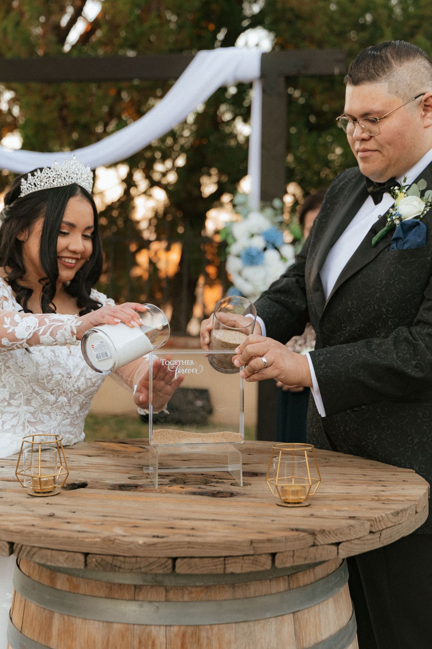 A couple performs a unity ceremony at their wedding using a rustic wine barrel table.