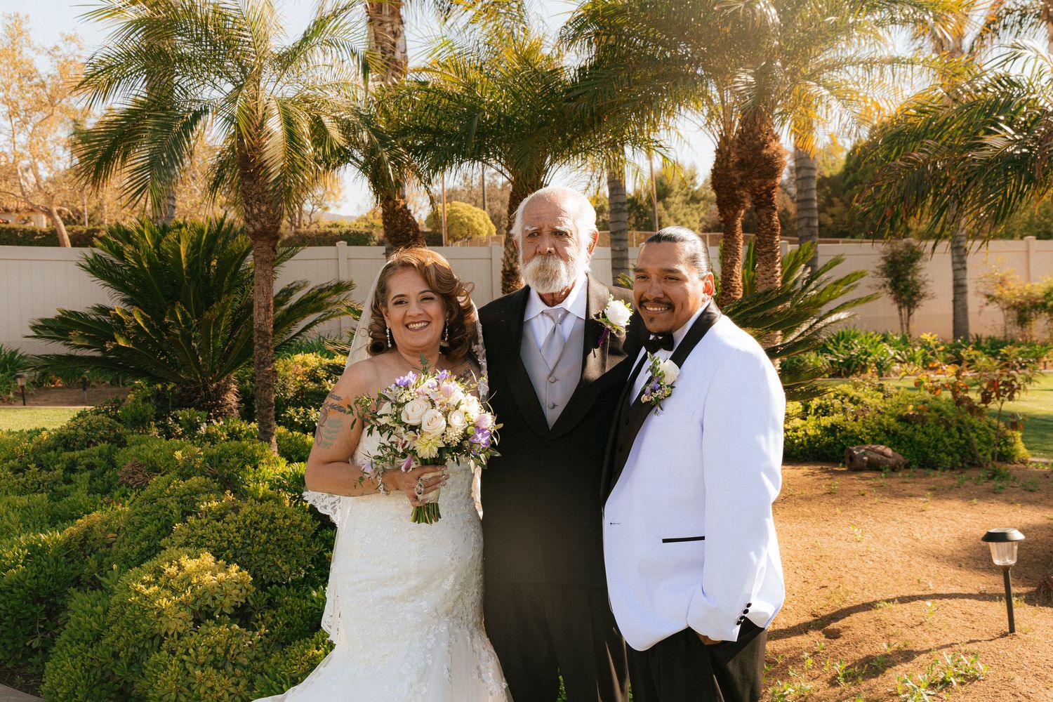 Romantic wedding photo session at sunset with palm trees and desert landscaping in the background.