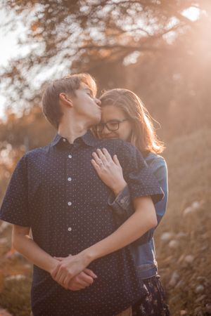 Romantic couple embracing in warm sunset lighting while wearing polka dot and casual attire.