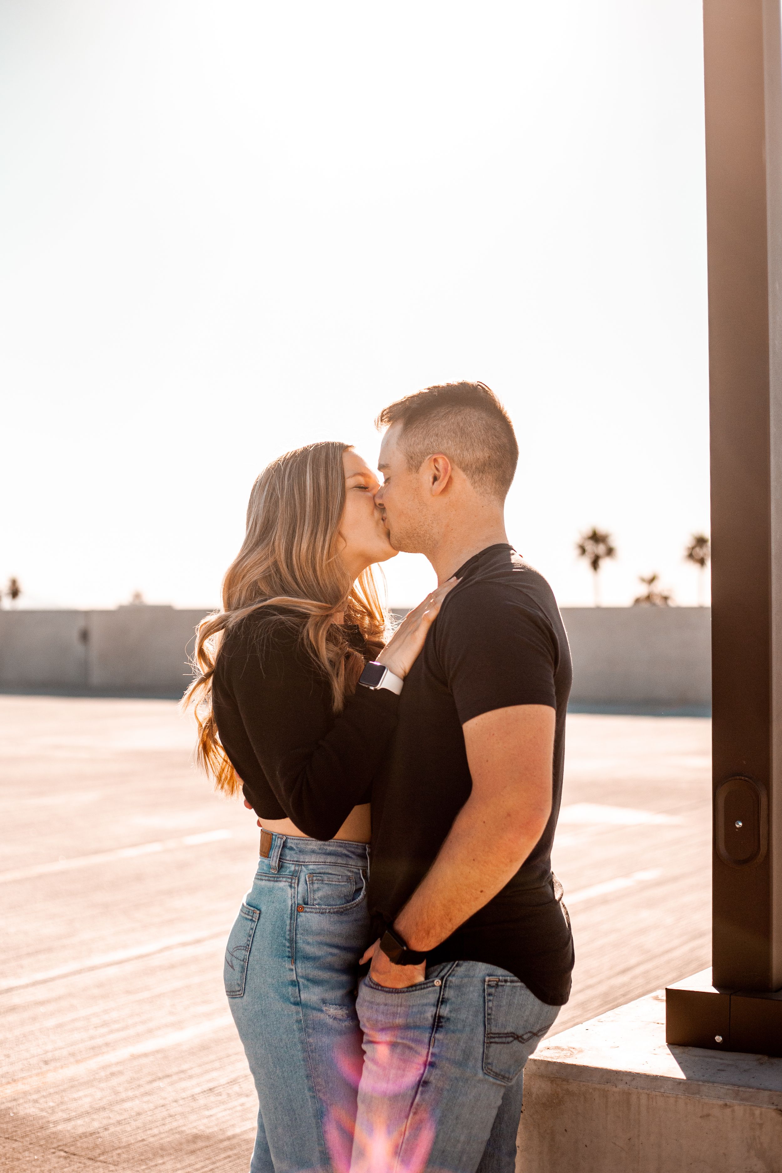 Couple sharing an intimate moment on a wooden deck during sunset.