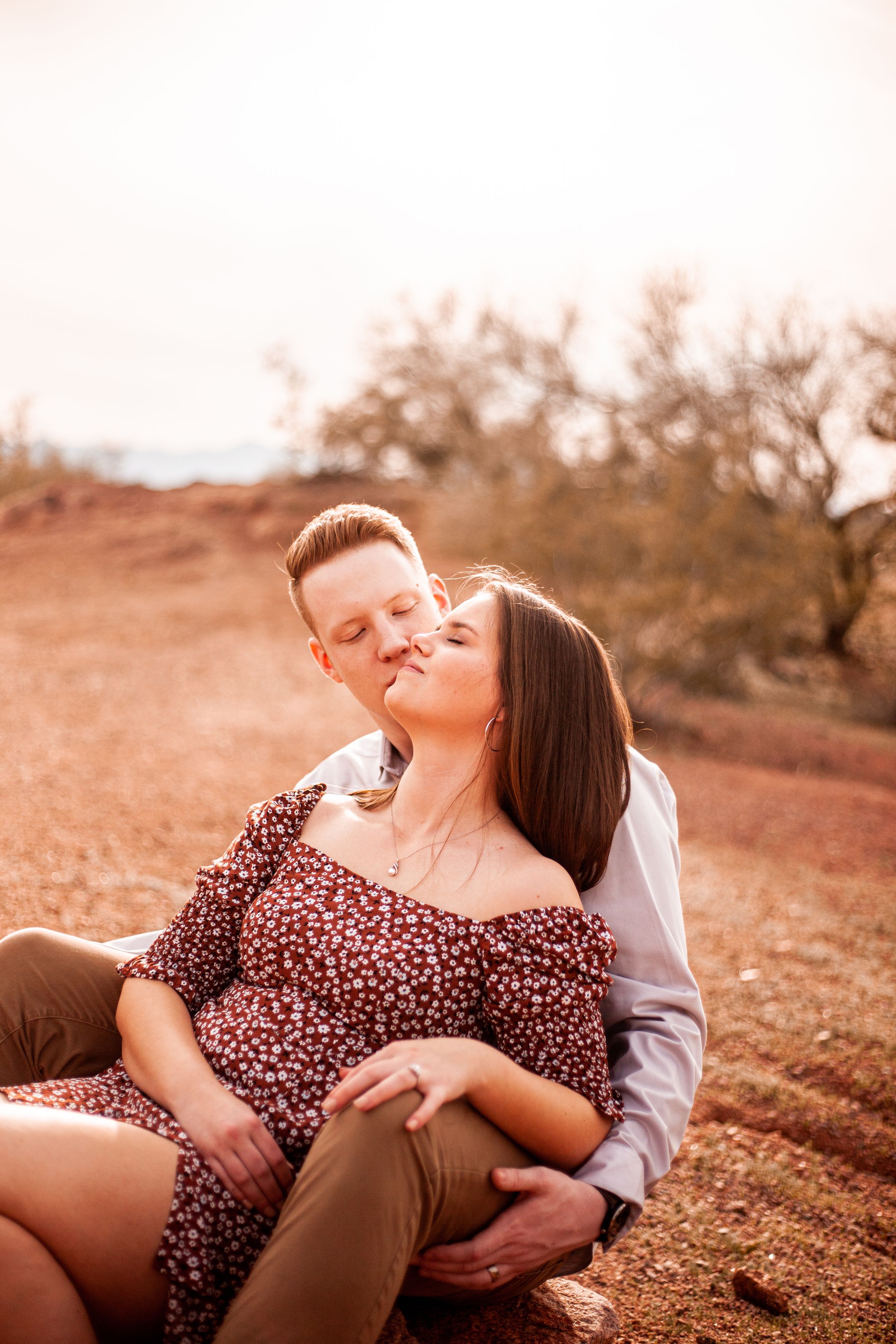 Romantic couple sitting together on red desert terrain during golden hour.