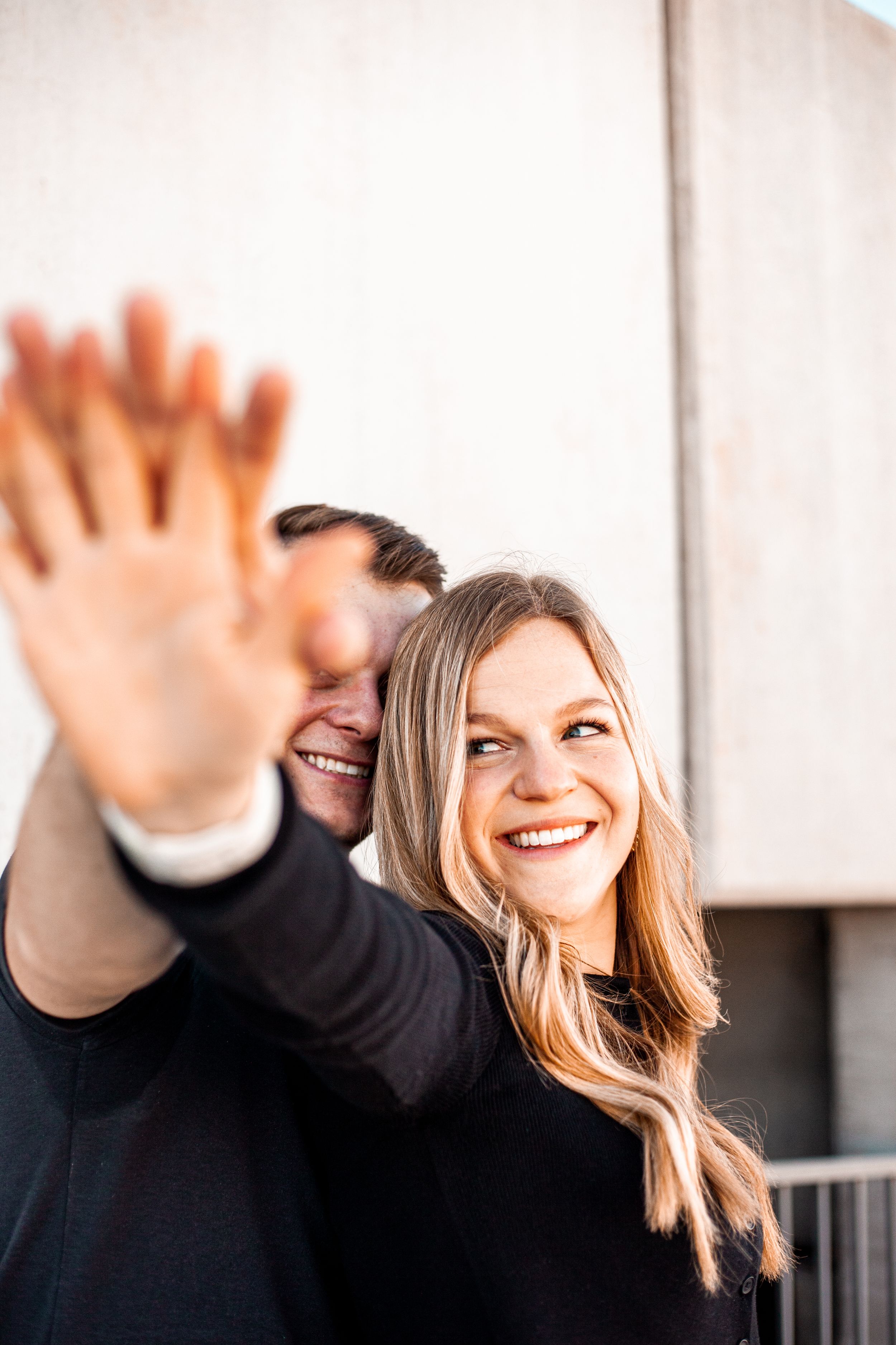 Playful moment captured as couple waves at camera with joyful expressions.