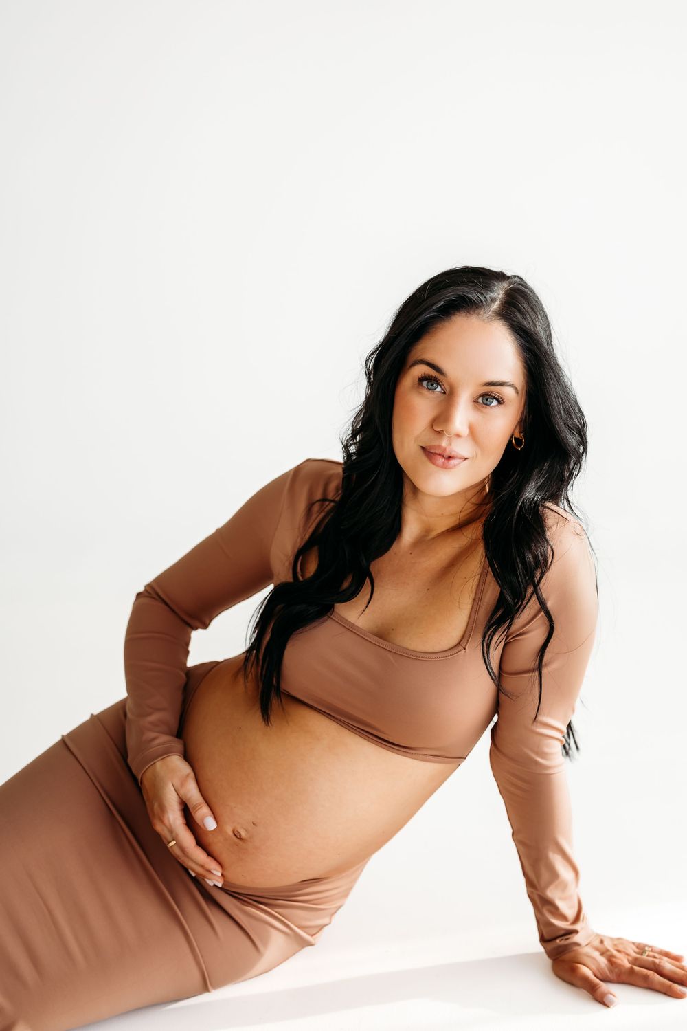 A person in a brown long-sleeved top poses against a white background in a creative photo series near Waterbury, CT