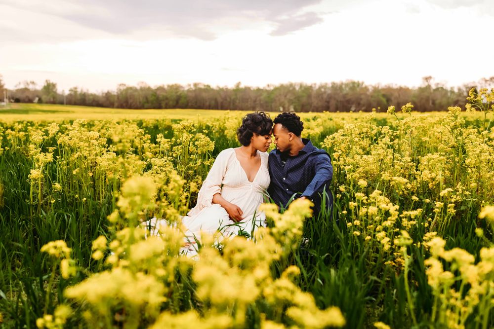 Romantic maternity photoshoot in a blooming yellow canola field with couple embracing in Bridgeport, CT.