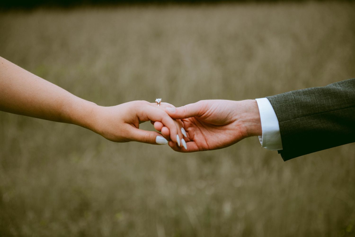 Closeup of Bride and groom loosely holding hands with wedding rings showcased