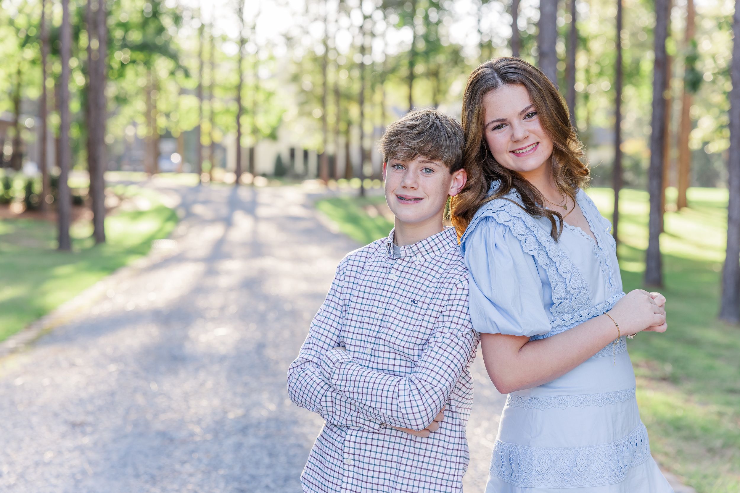 A family enjoys a playful moment together on a tree-lined path during an outdoor photo session.