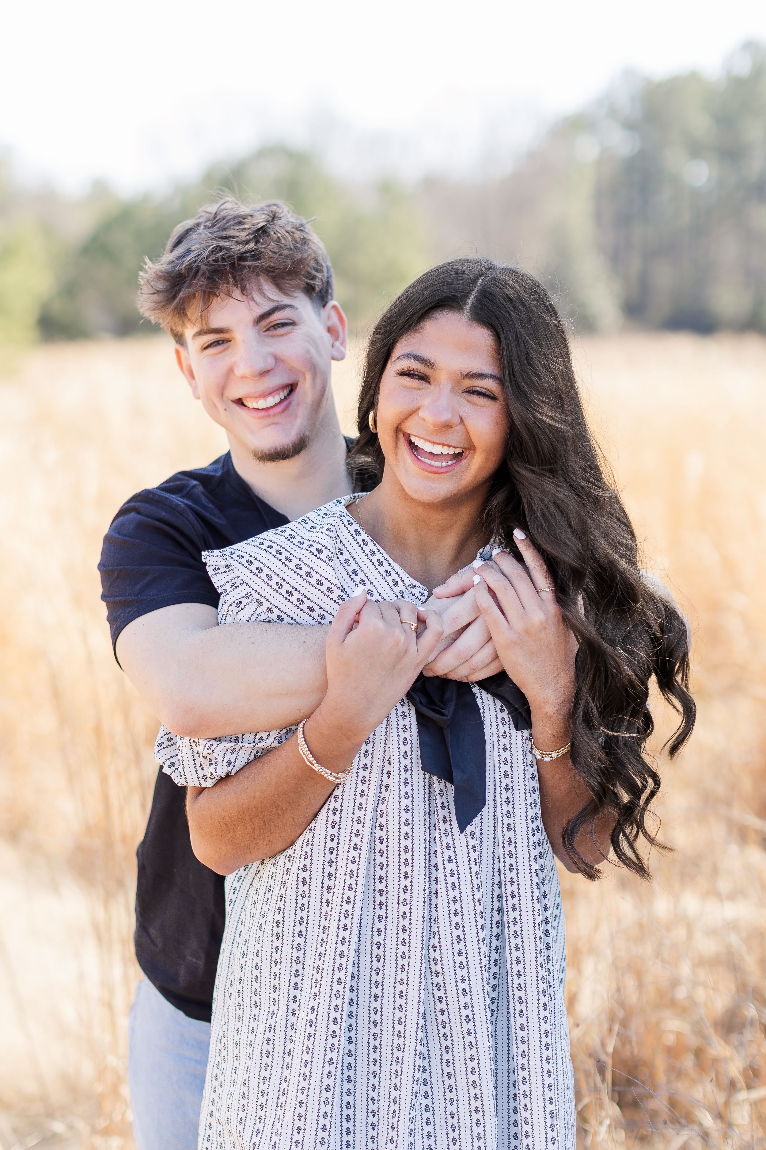 A couple shares joyful moments together in a golden field during an outdoor photo session.