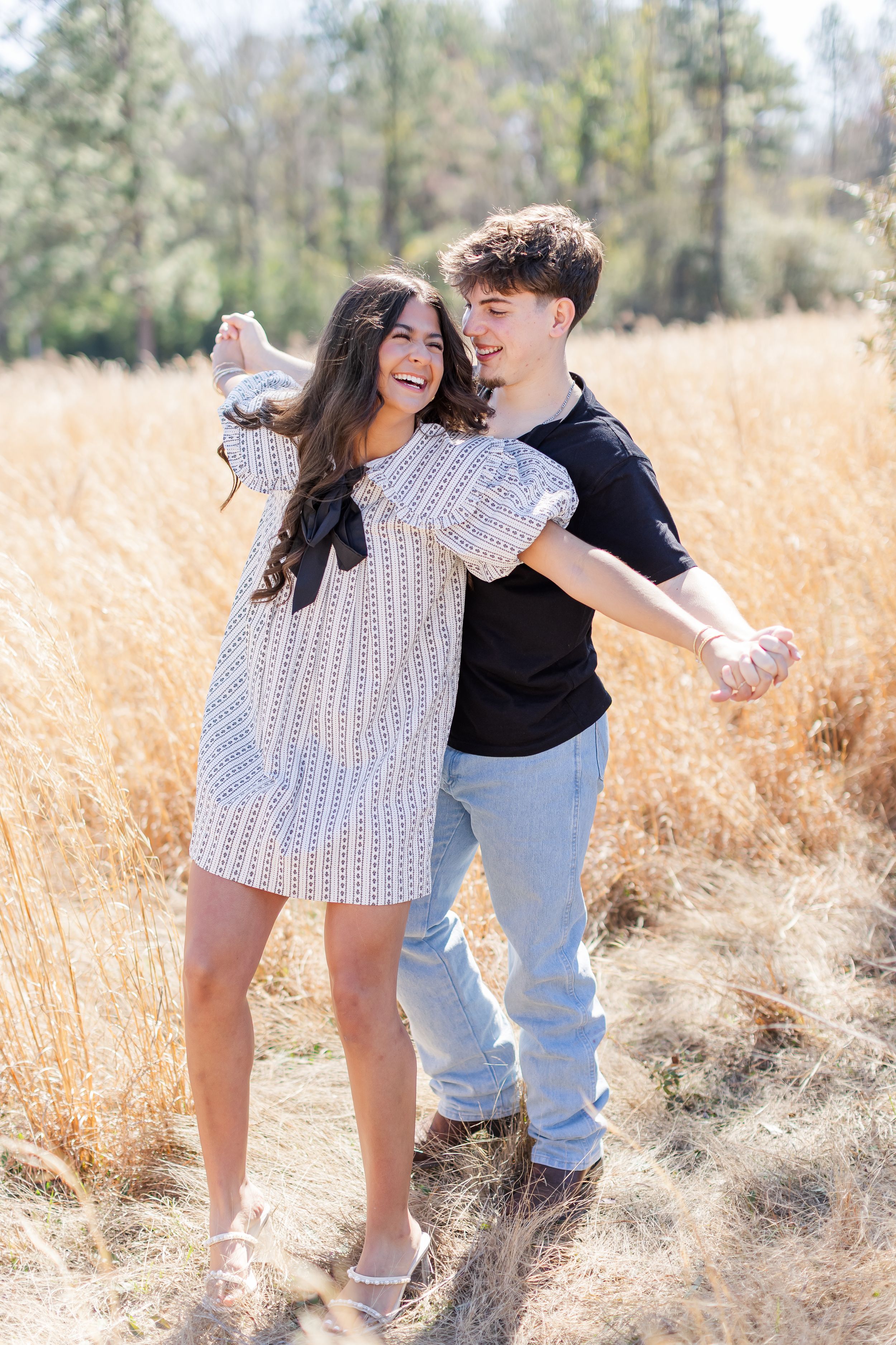 A couple playfully poses together in a golden wheat field on a sunny day.