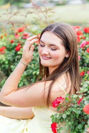 Artistic portraits among red roses in garden with soft natural lighting.