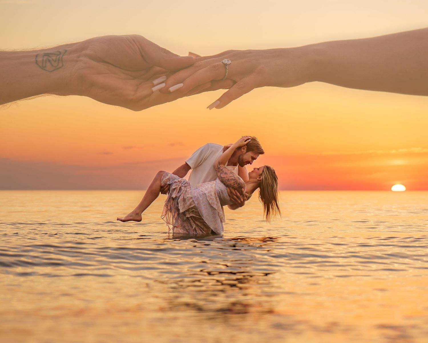 Two silhouetted hands reach towards each other against a sunset sky with bright sun between them.