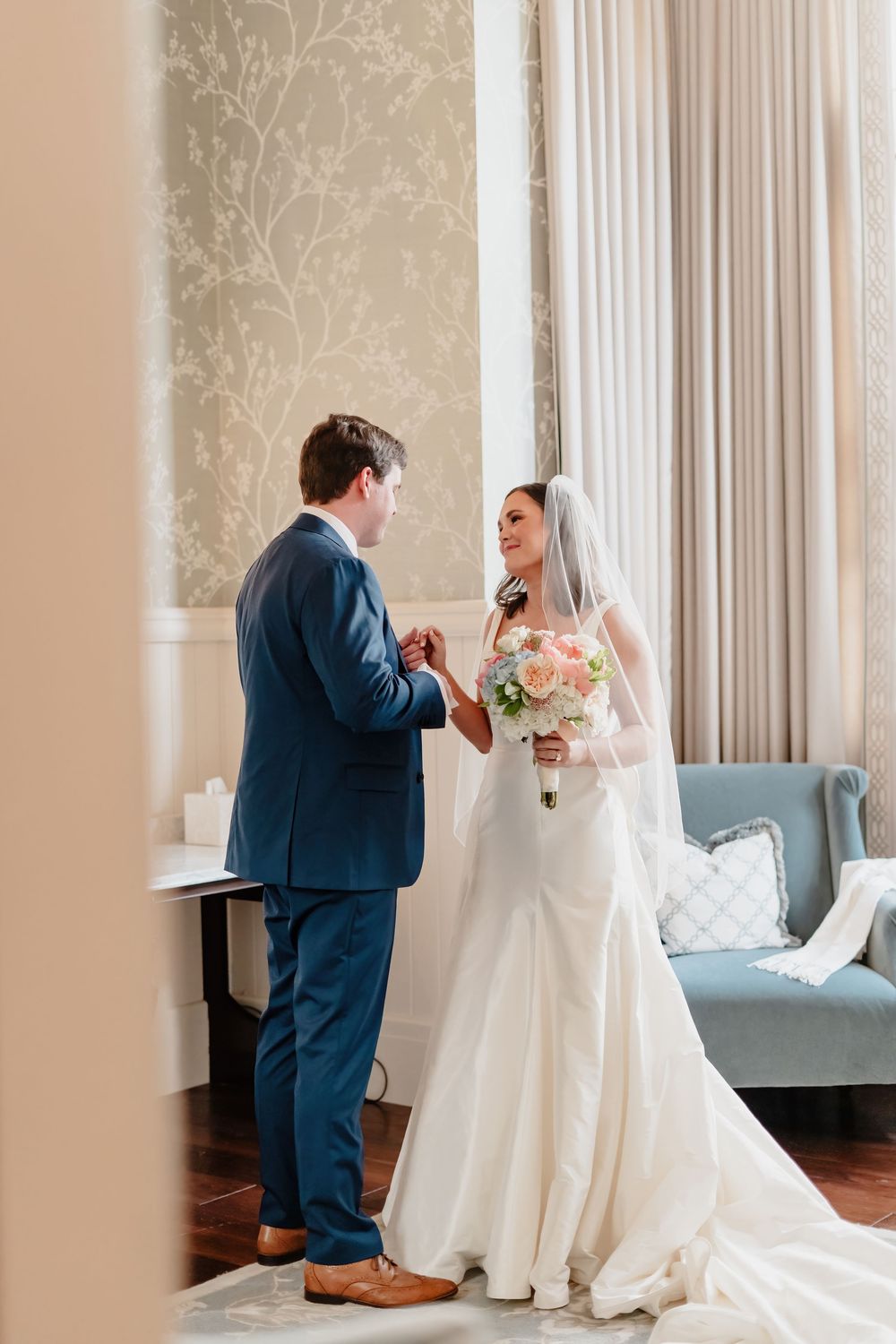 A series of candid first look wedding photos showing a groom and bride in a white dress meeting in an elegant room.
