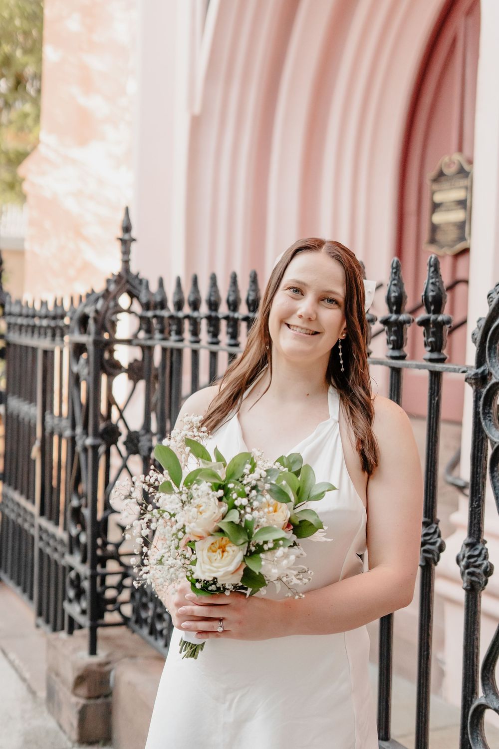 Panoramic collection showing bride with white bouquet standing against pink wall and black iron fence in elegant setting.