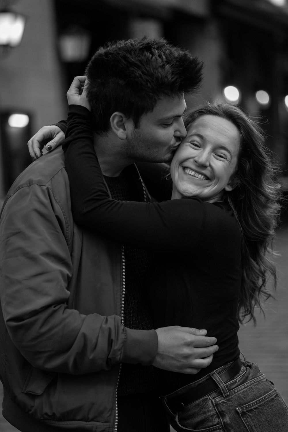 Black and white photo series showing a couple sharing intimate moments and embraces on a city street at night.