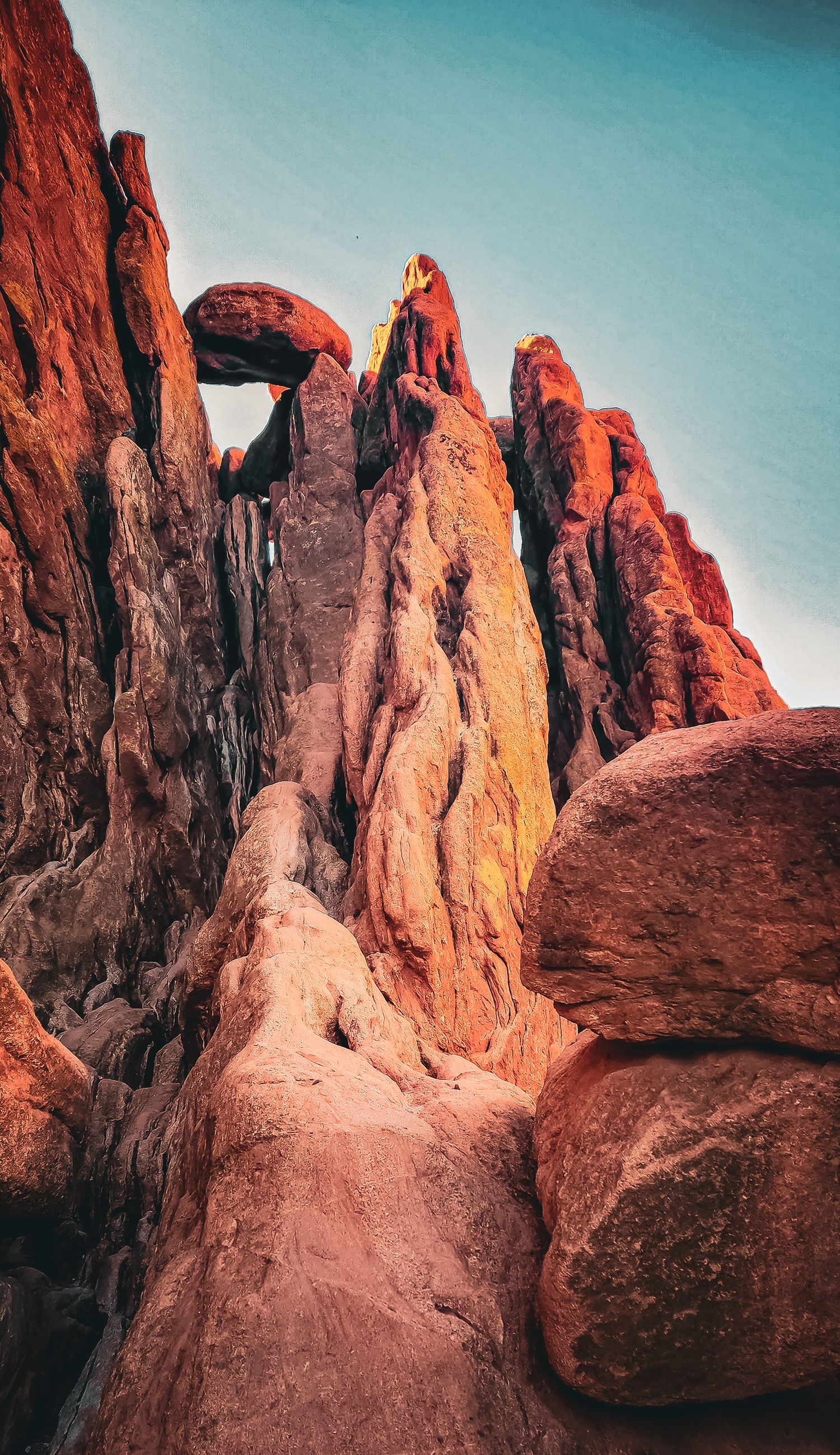 Towering red rock formations glowing in warm sunlight against clear blue sky.