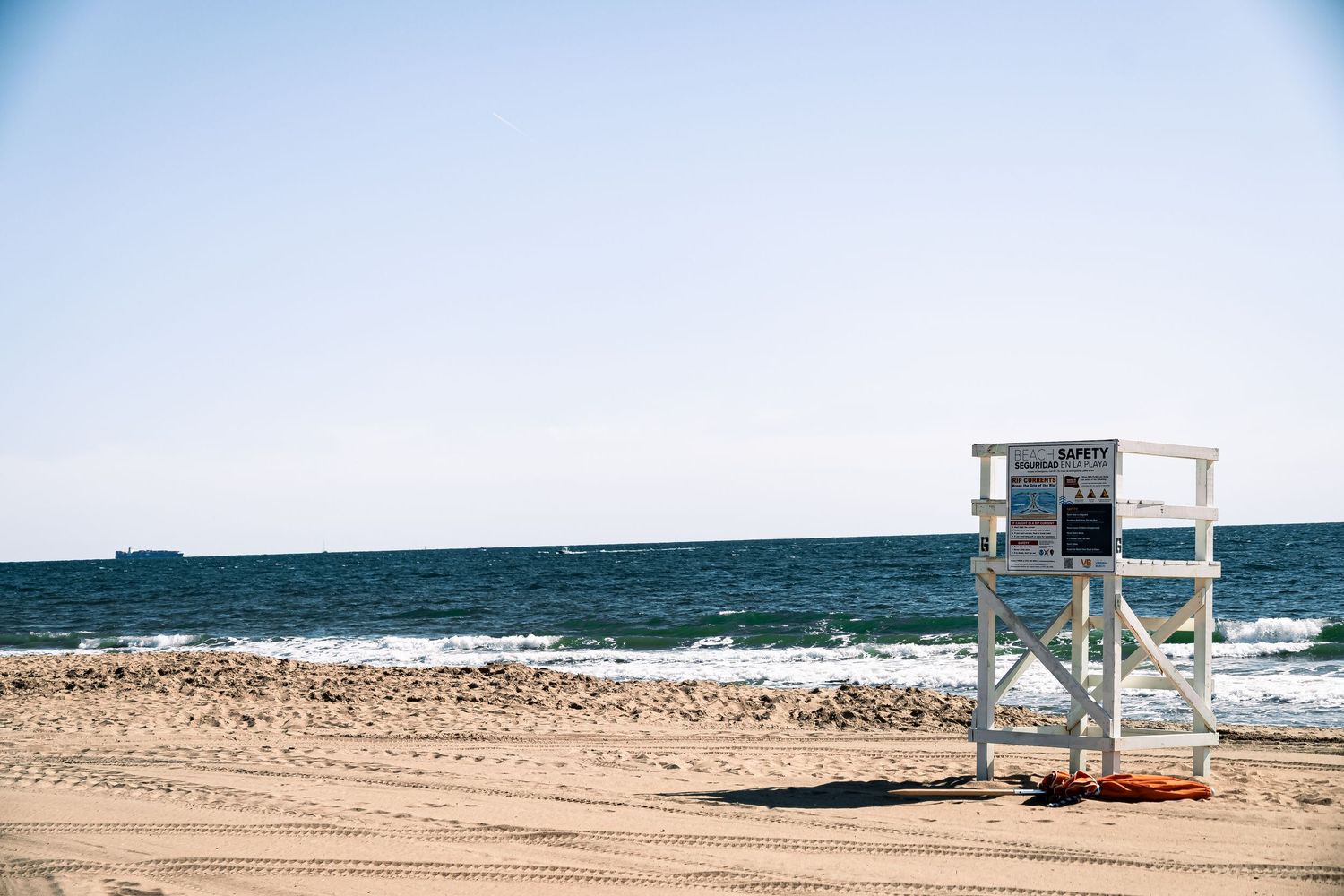 A lifeguard tower stands on a sandy beach with turquoise ocean waters and clear blue skies in the background.