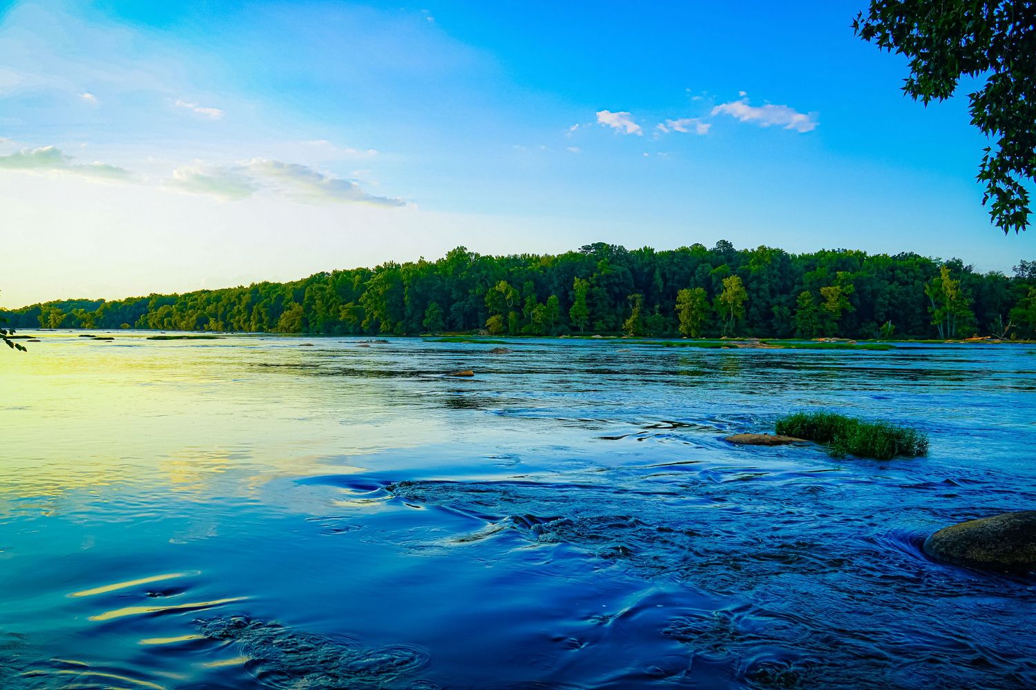 Serene lake waters reflect surrounding forest and sky in vibrant blue tones.