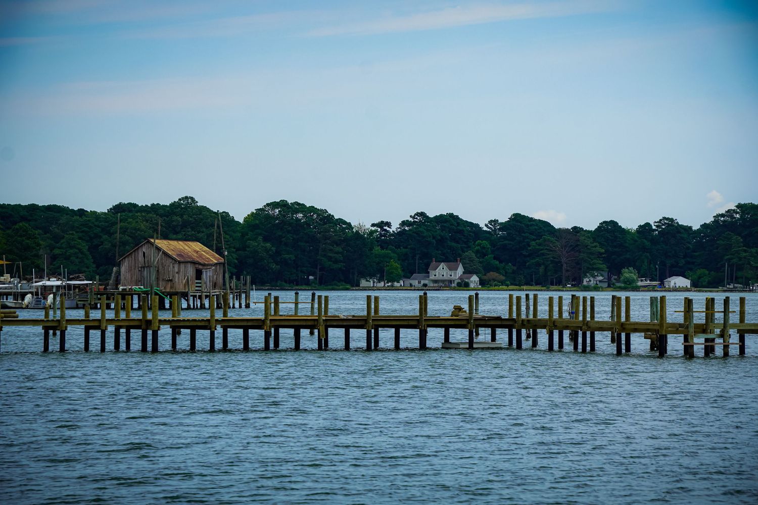 A long wooden pier with small buildings stretches across the calm bay waters.