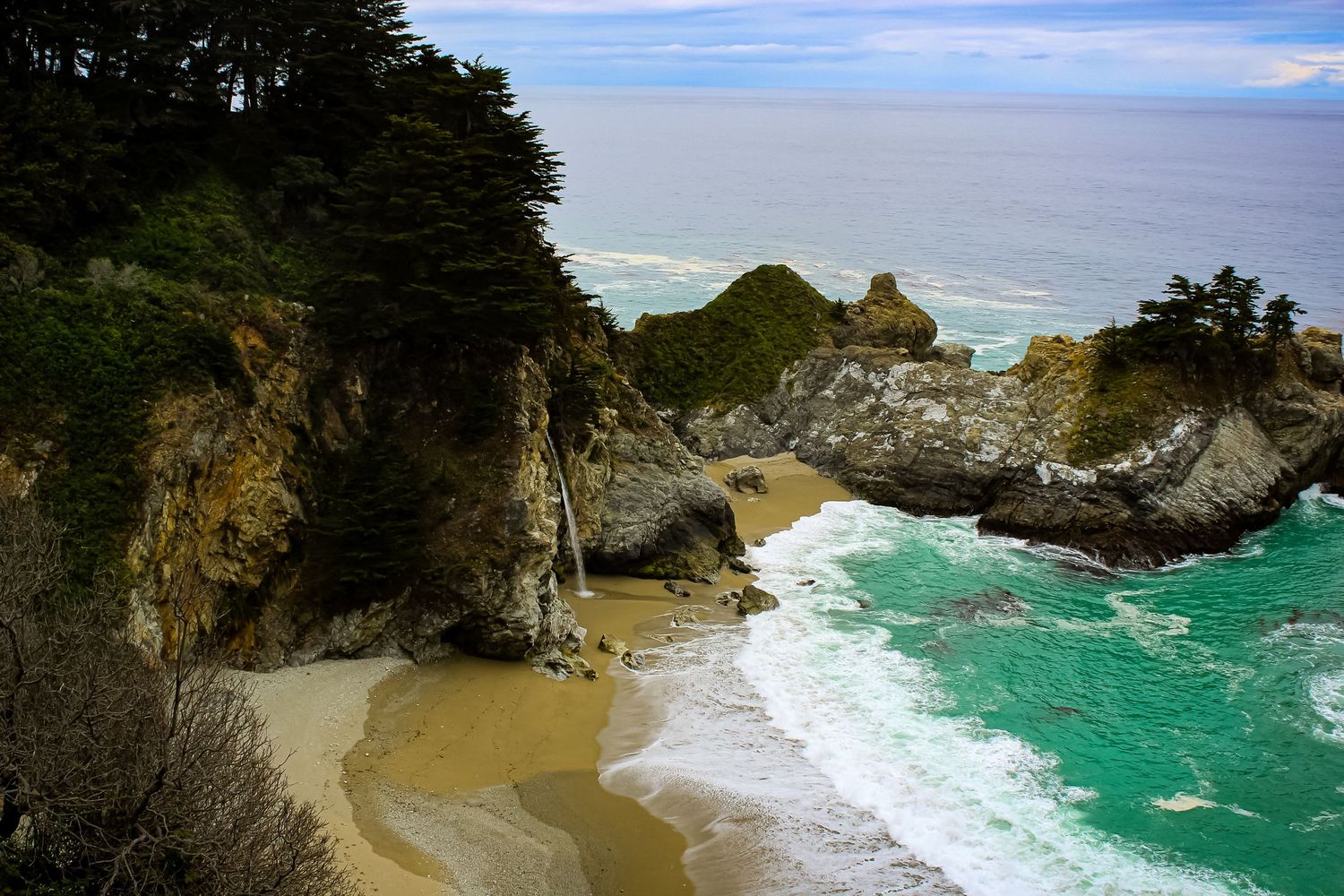 Hidden beach cove with turquoise waters surrounded by dramatic coastal cliffs.