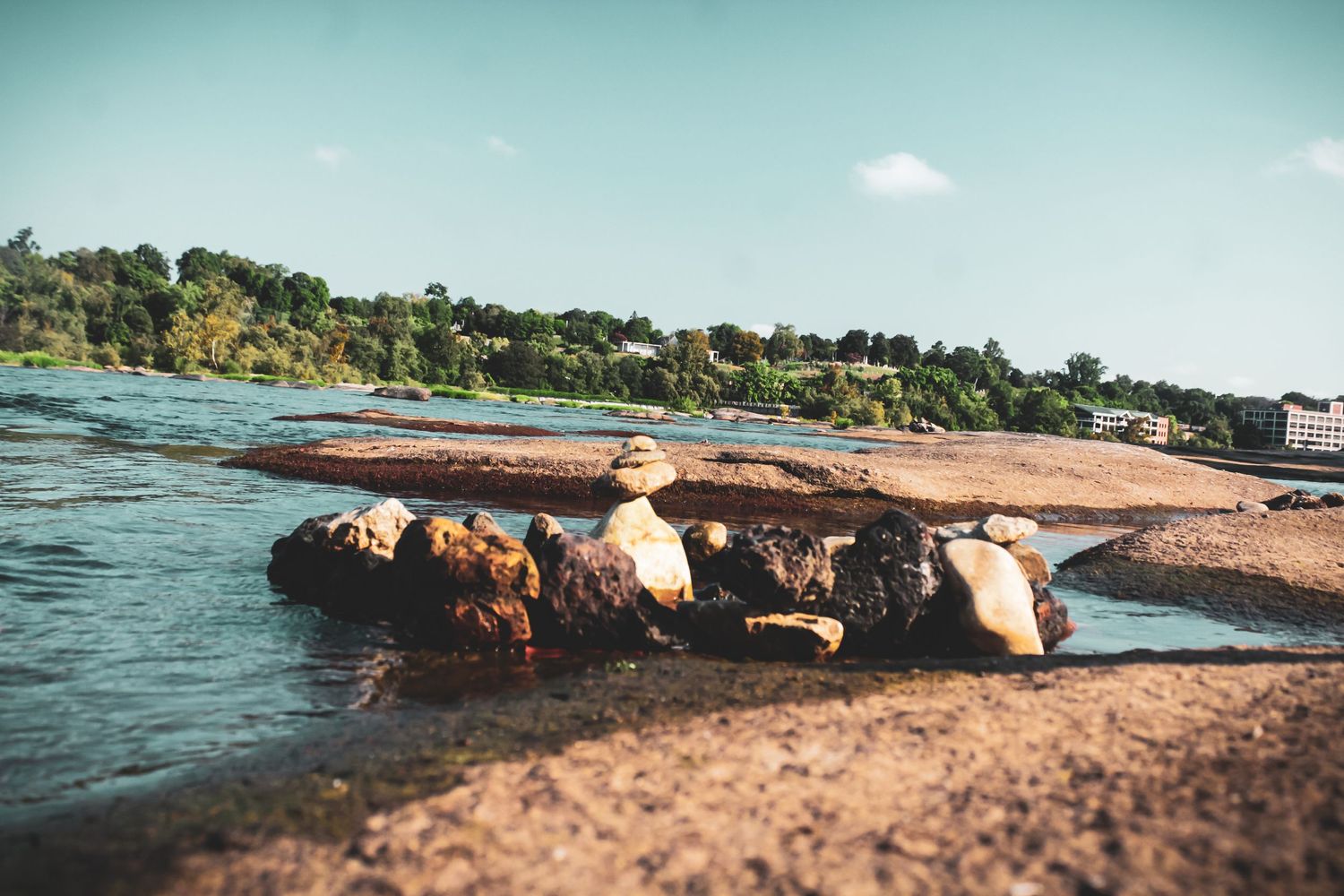 Large rocks and boulders along a riverbank with trees in the background.