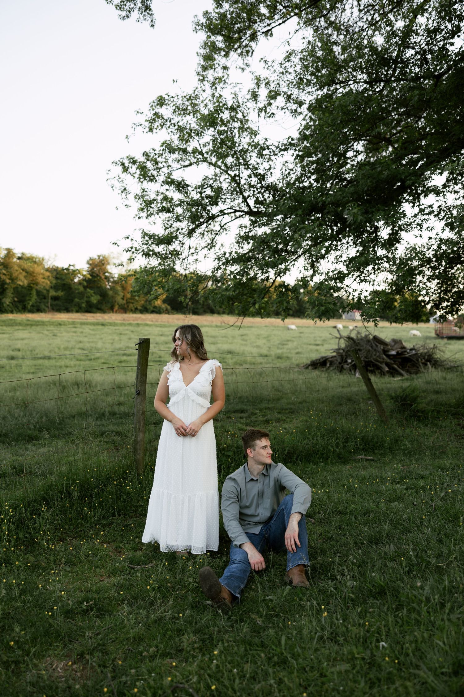 Couple sitting together in a serene meadow during golden hour.