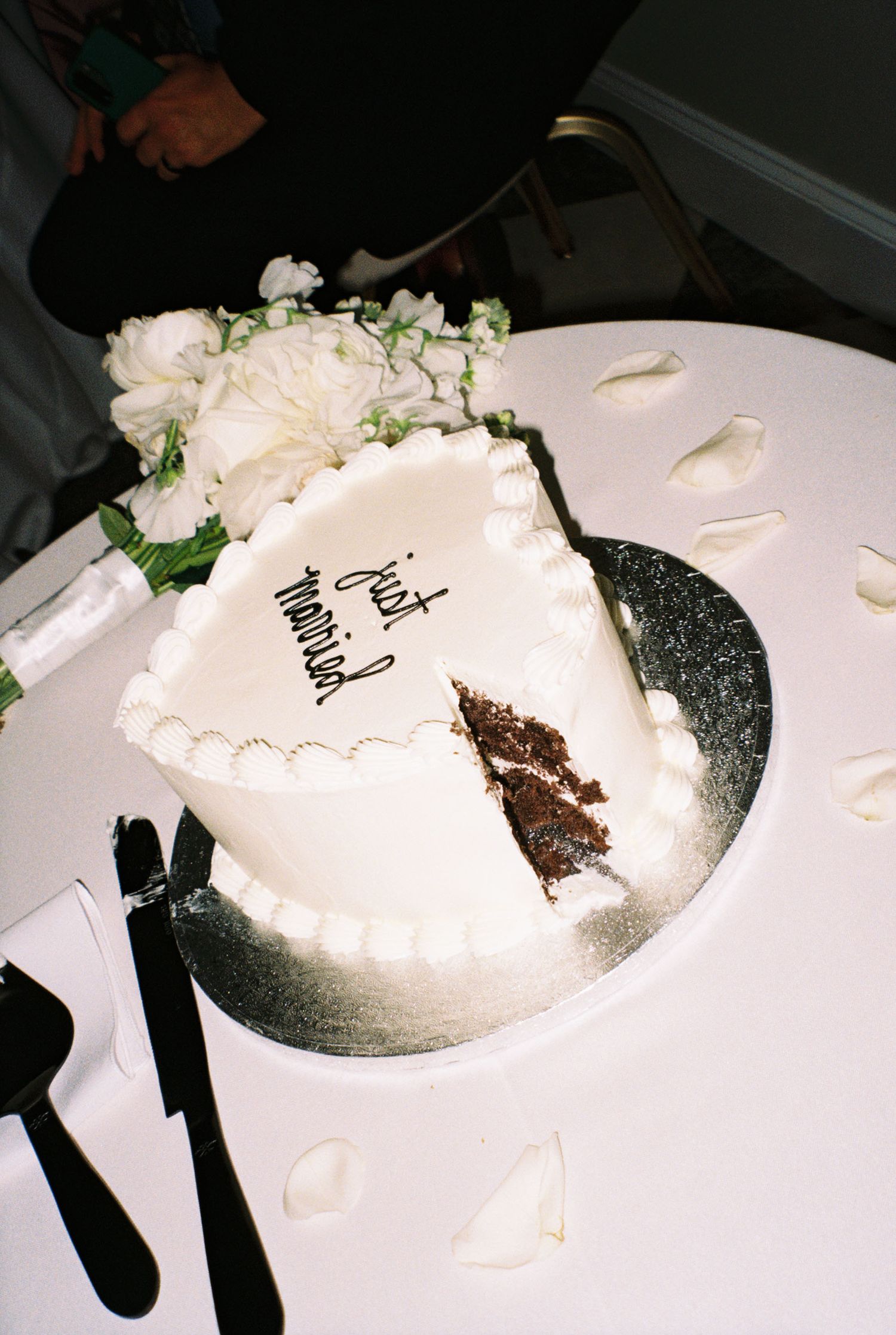 White wedding cake being cut and served on a silver platter.