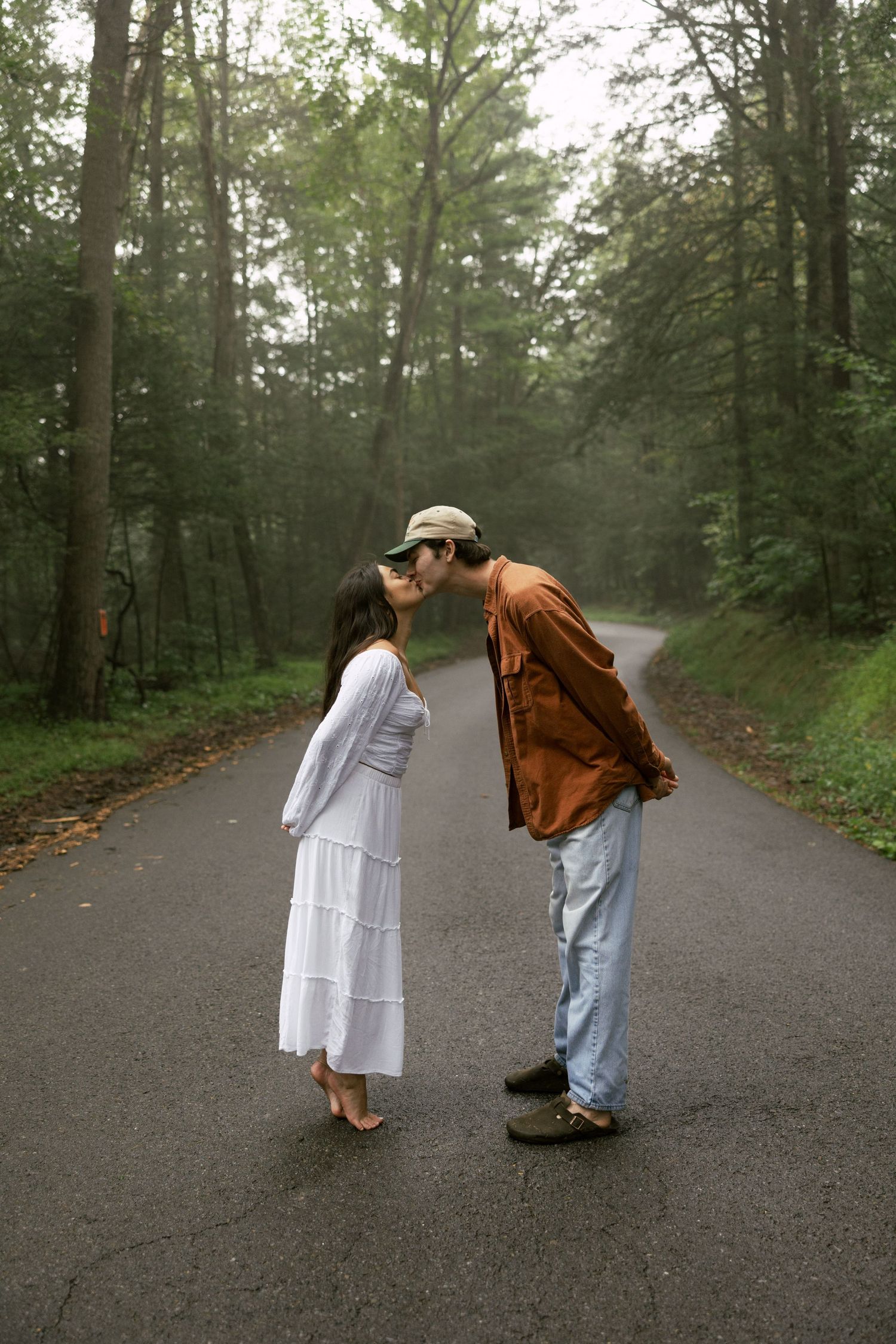 Two people playfully bowing to each other on a misty forest path.