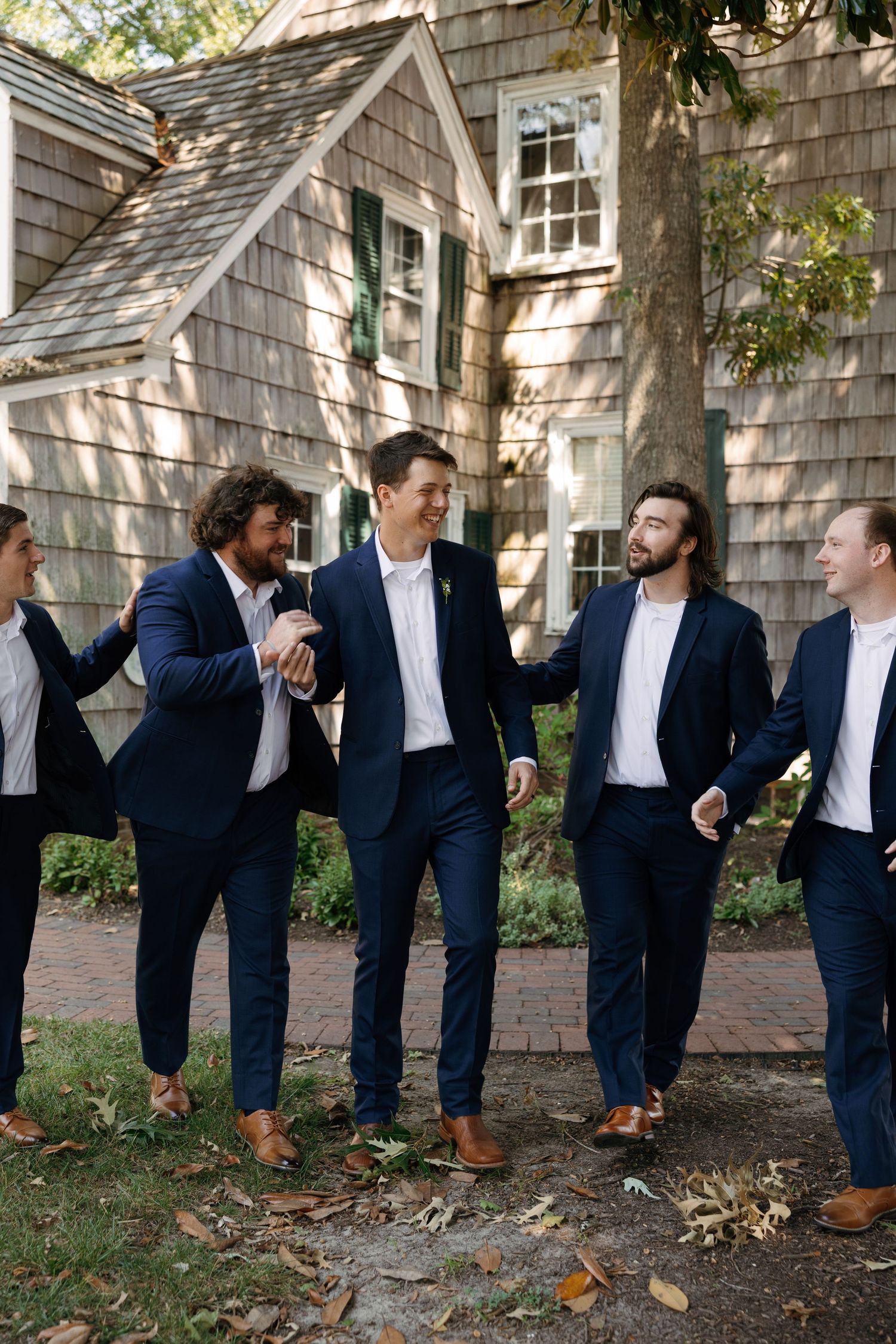 A creative photo sequence showing groomsmen in navy suits leaning against a cedar shake wall in domino effect style.