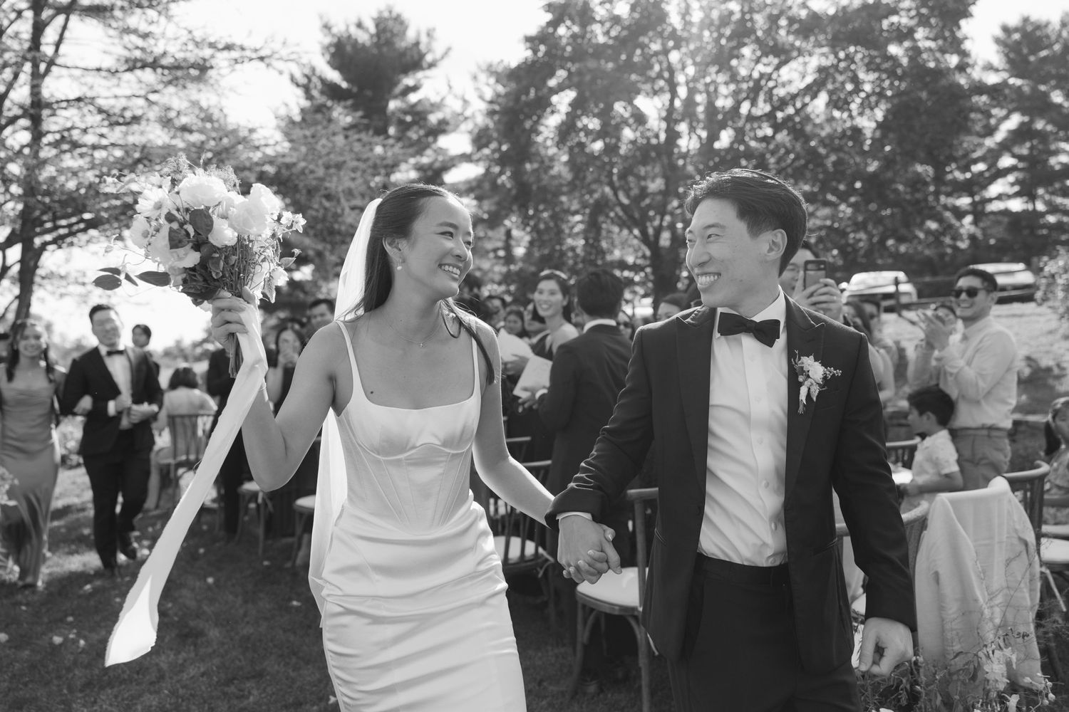 Newlyweds walking joyfully through their outdoor wedding celebration.