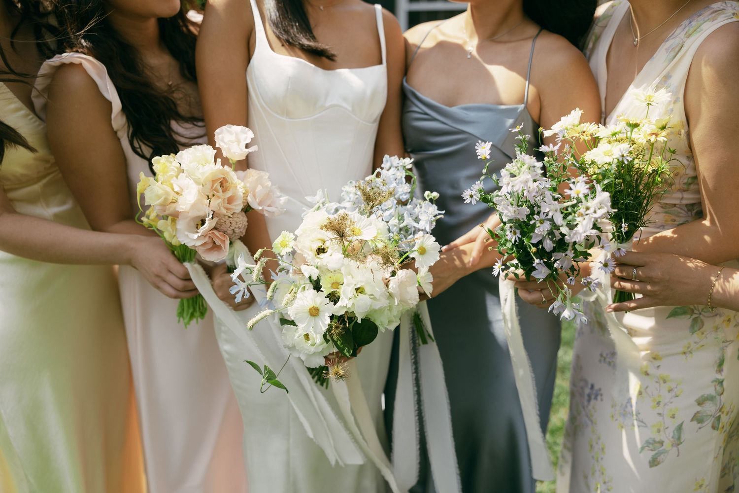 Bridesmaids holding elegant pastel floral bouquets at a wedding.