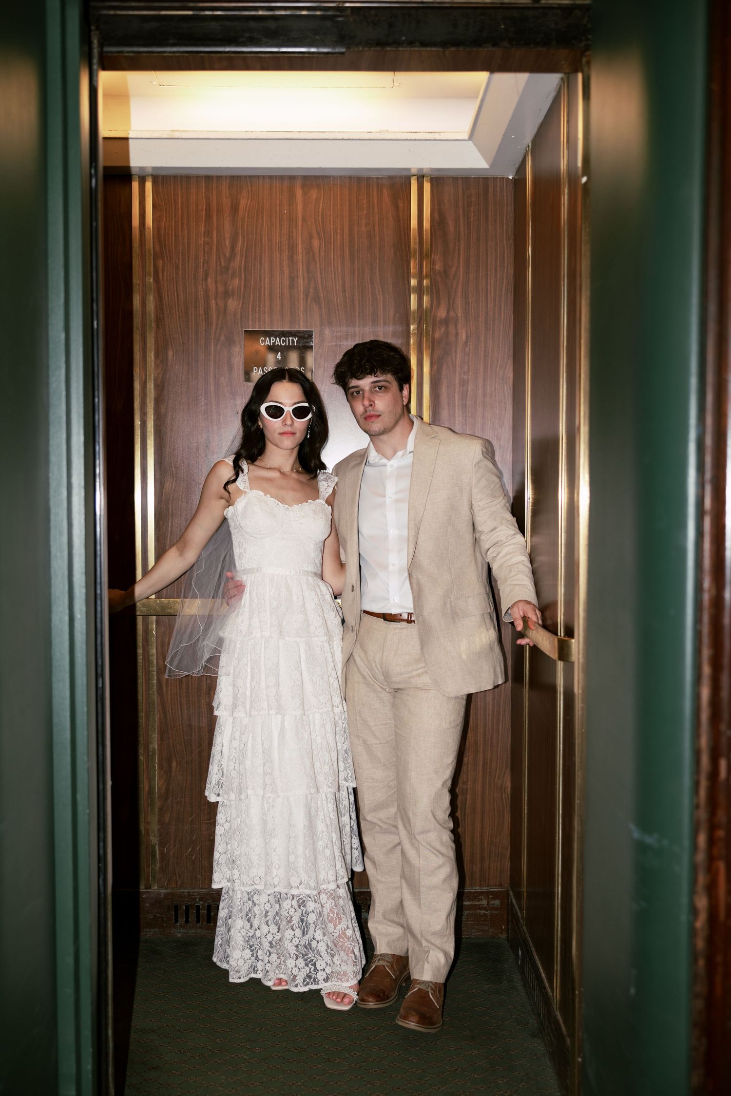 A couple walks down an elegant hallway in formal wedding attire.
