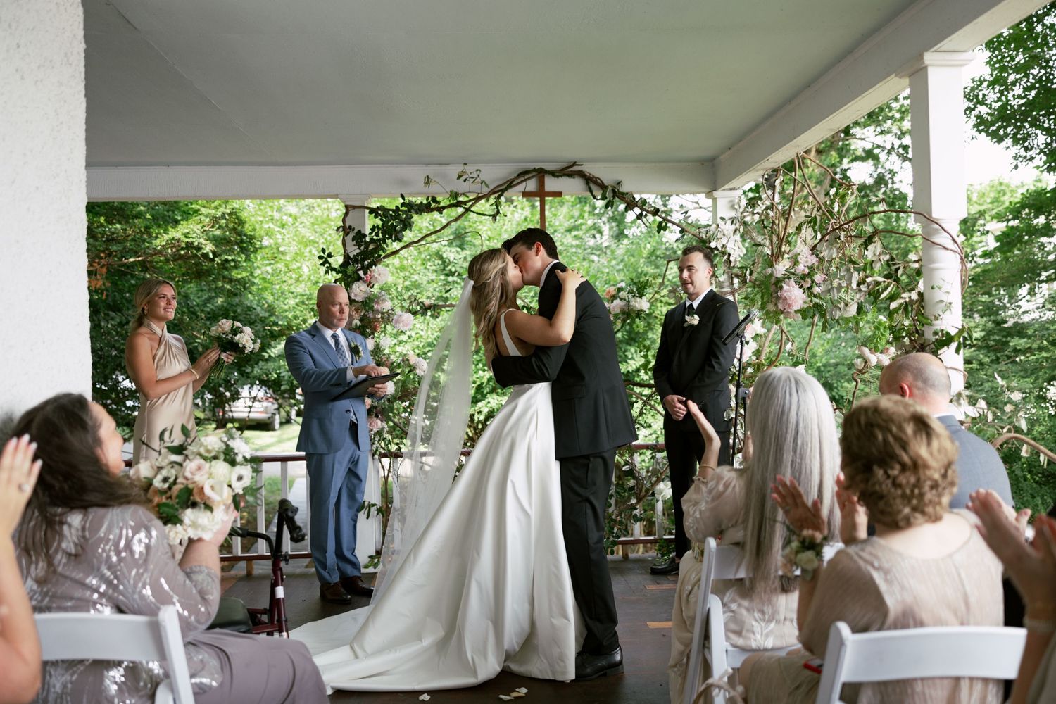 Wedding celebration on a covered porch with guests gathered to celebrate.