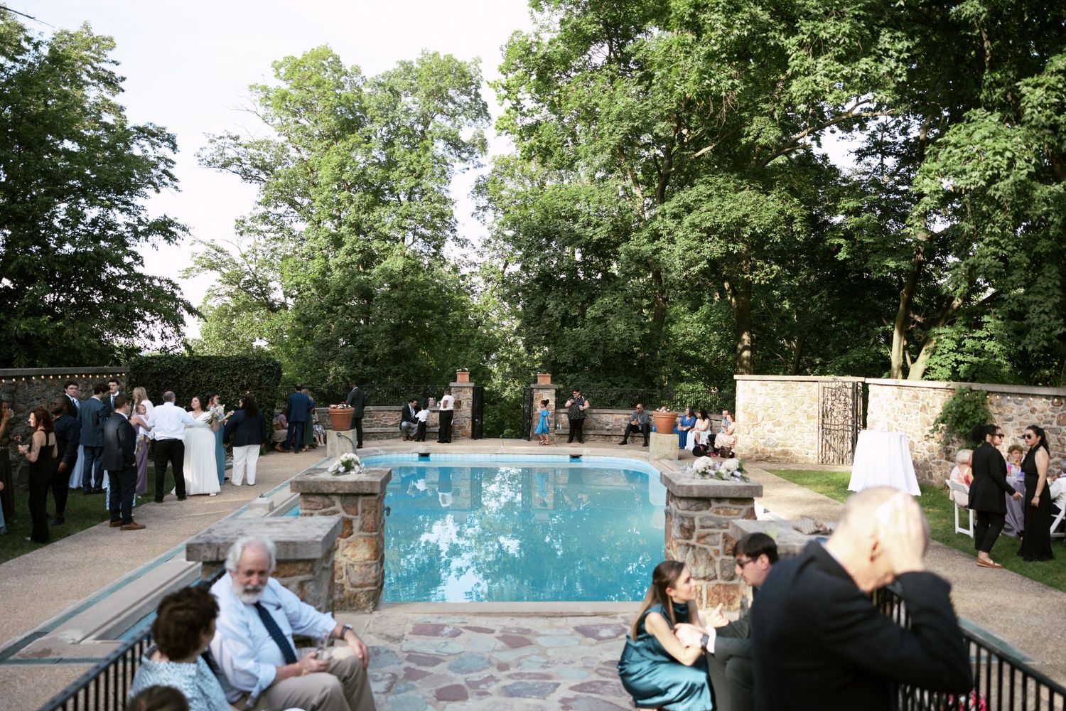 A panoramic view of guests gathered around an outdoor swimming pool area.