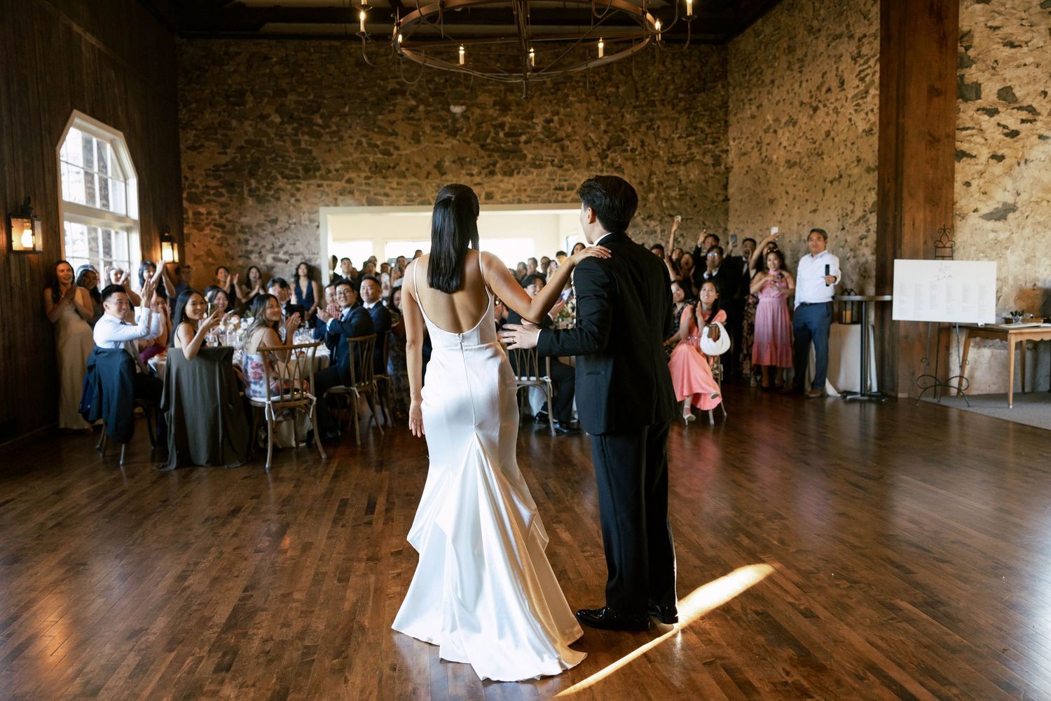 Panoramic view of a rustic wedding reception venue with stone walls and hardwood floors.