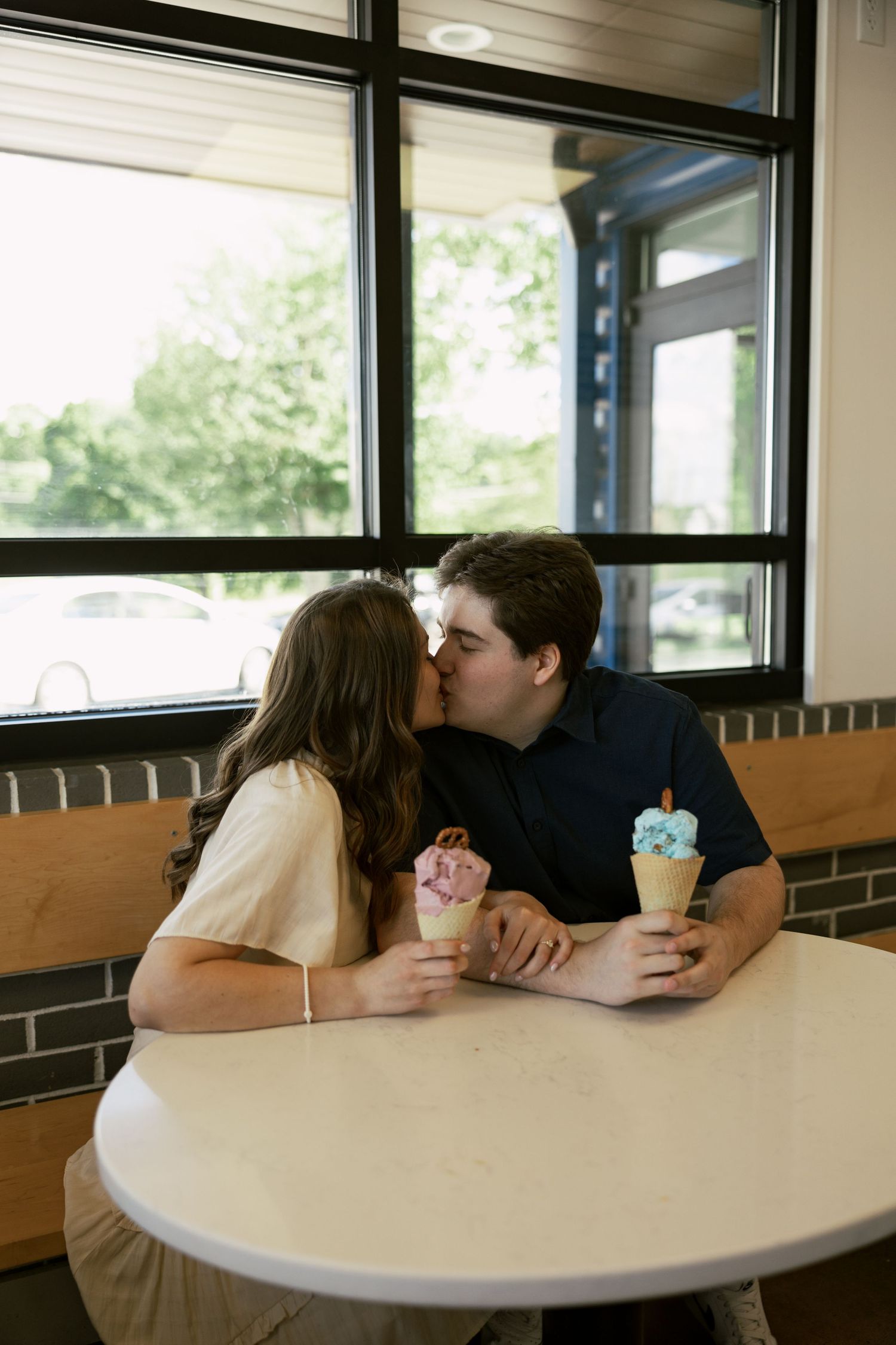 Couple enjoying ice cream together at a retro diner booth near a window.