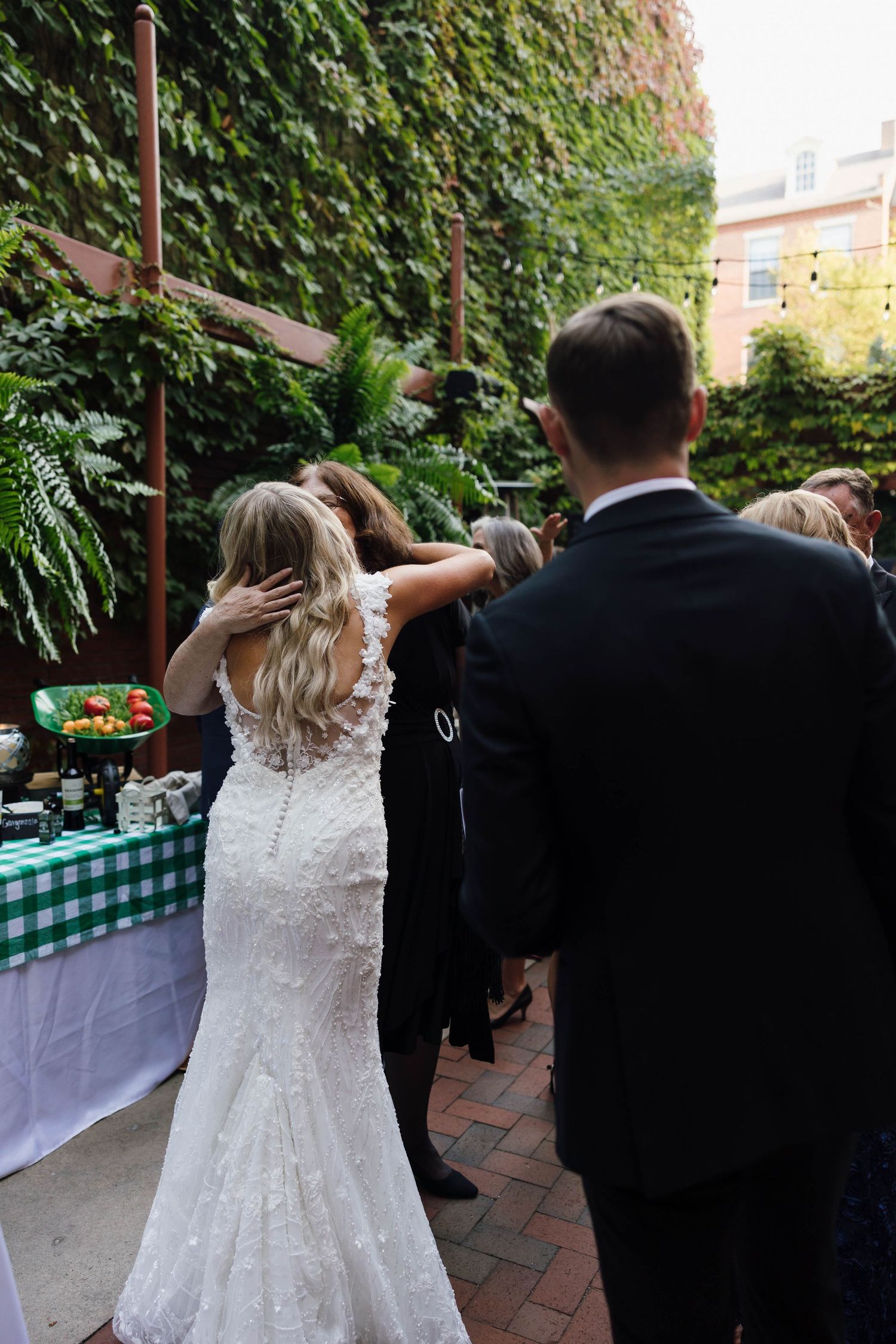 Wedding celebration on an ivy-covered patio with guests enjoying refreshments.