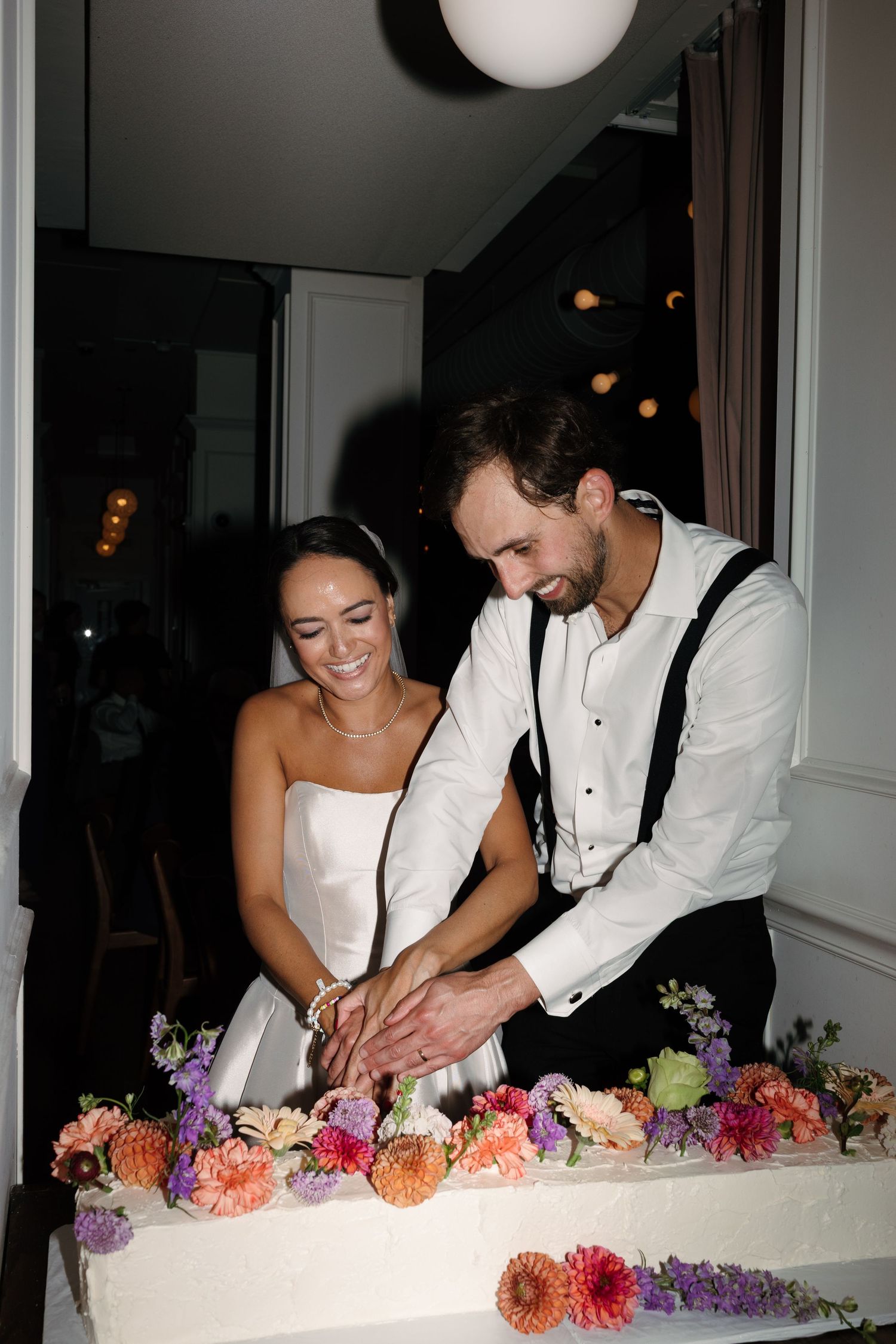 Newlyweds cutting their wedding cake decorated with colorful flowers.