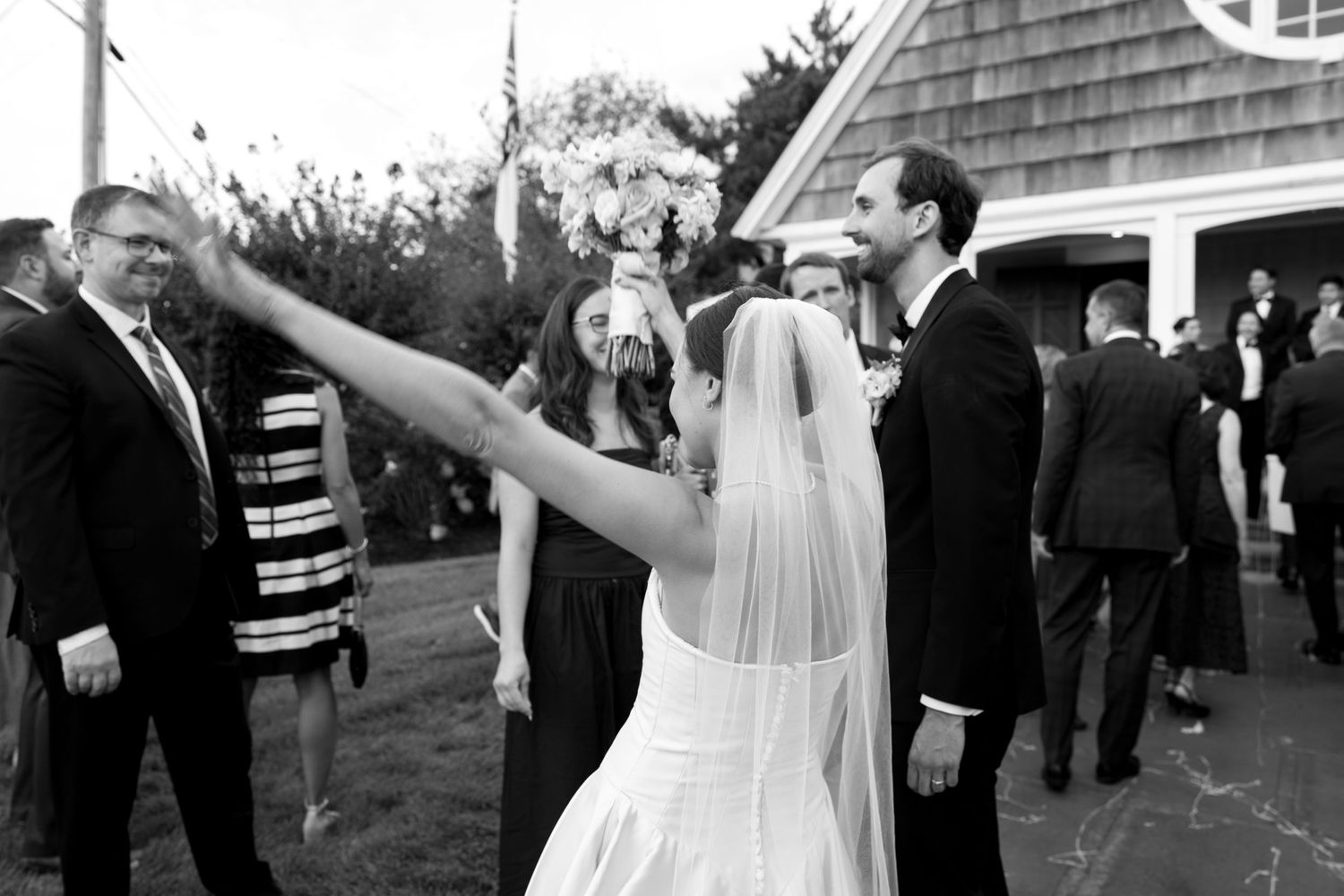 Wedding party celebrates with joyful dancing and movement at an outdoor reception.