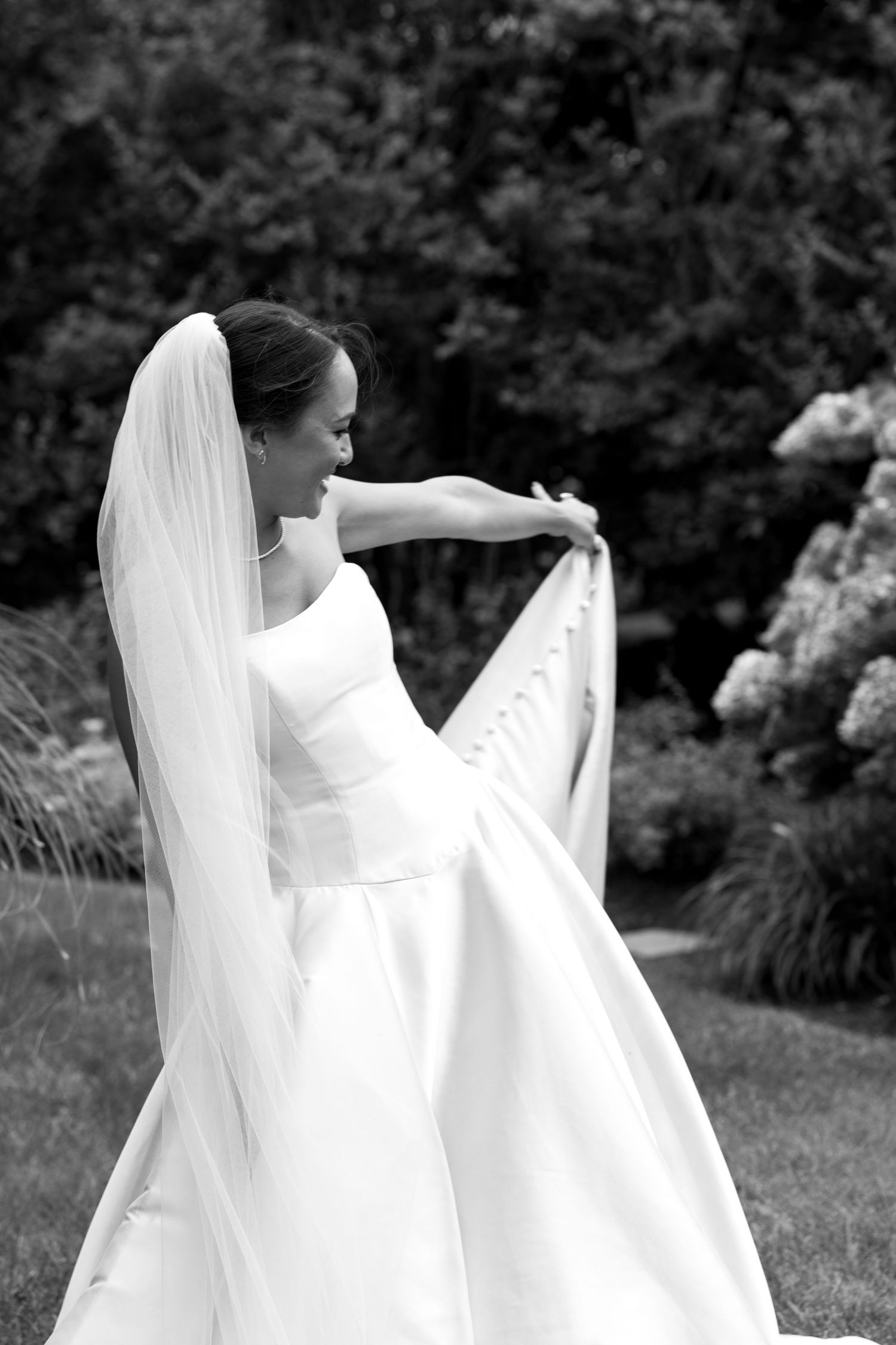 Elegant bridal portrait showcasing flowing white wedding dress and veil outdoors.