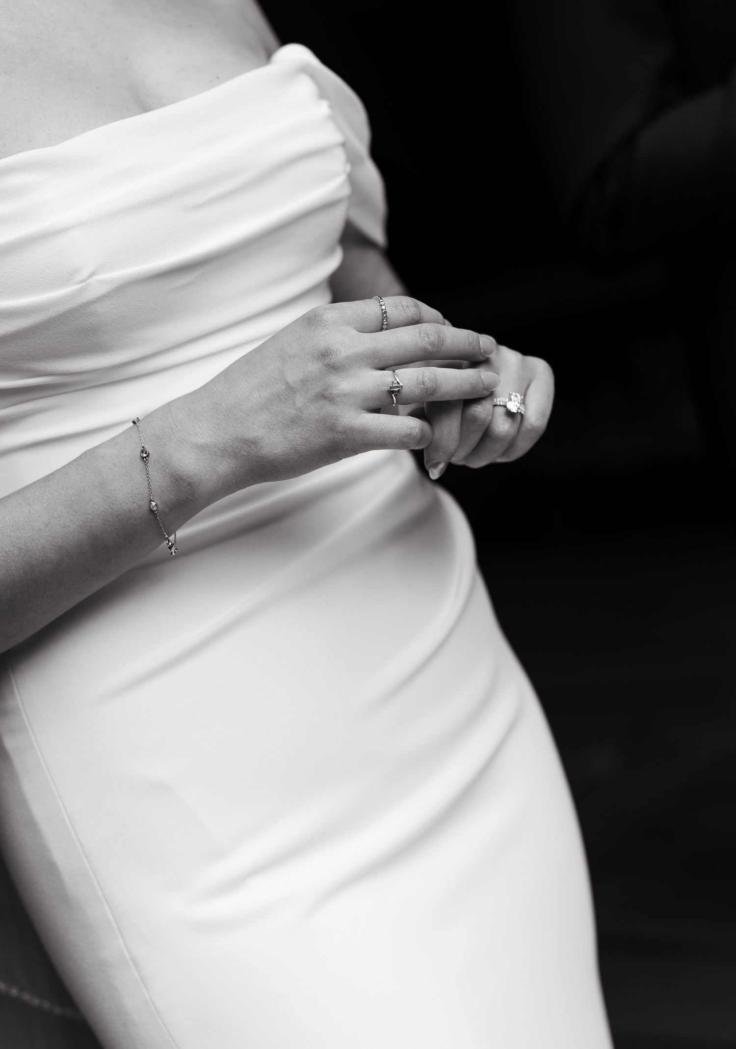 Close-up details of a white wedding dress fabric and jewelry.