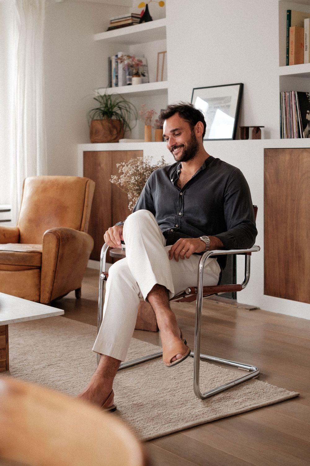 Interior lifestyle shot of person relaxing in modern chair with built-in shelving background.