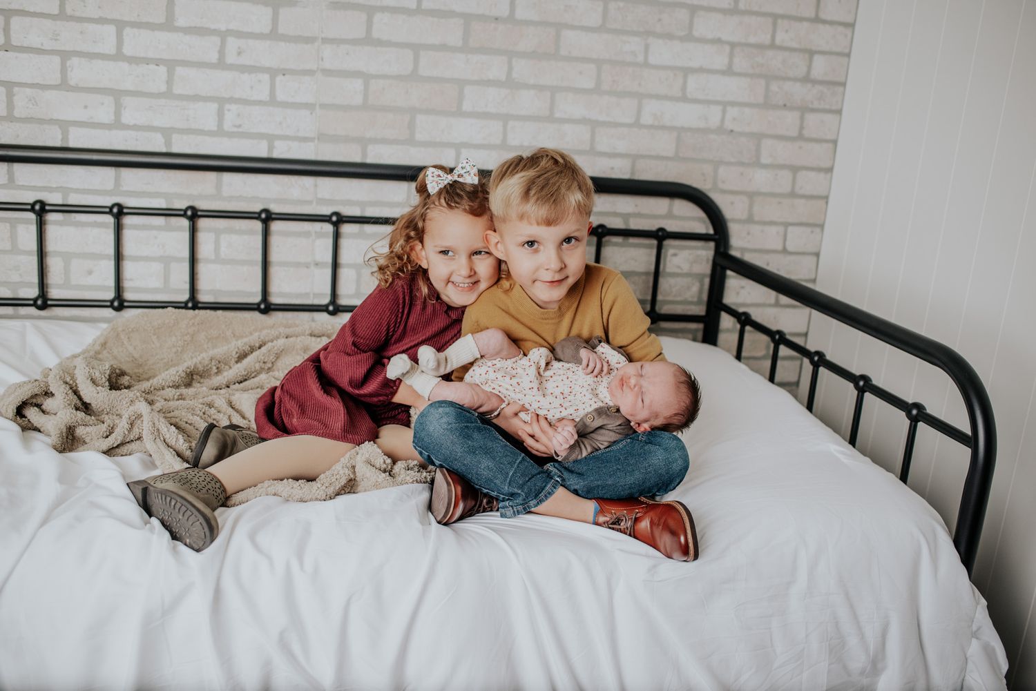 Lifestyle photos of family members cuddling together on a bed with white linens.