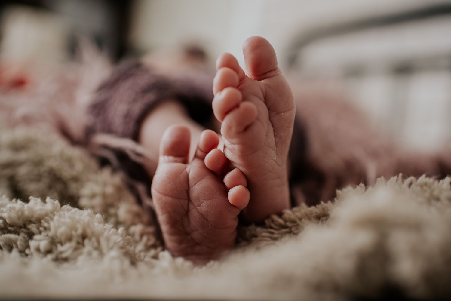 Close-up detail shots of tiny baby feet against soft textured fabric.