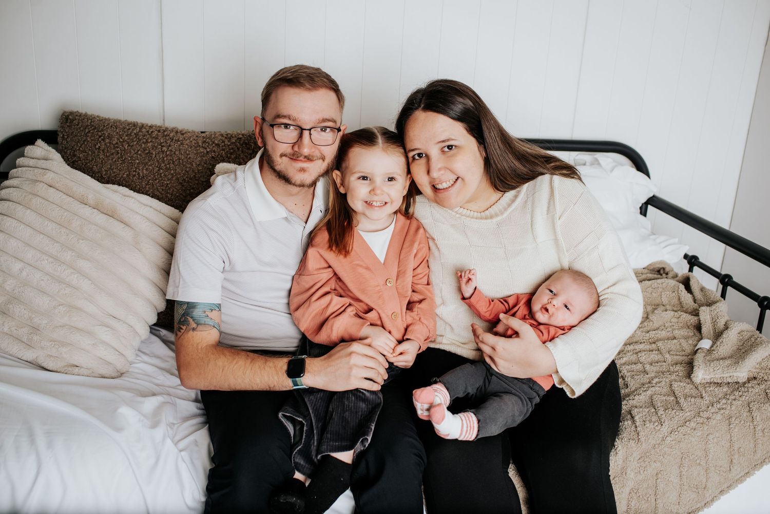 Intimate lifestyle photos of a family relaxing together on a white bed during newborn photoshoot.