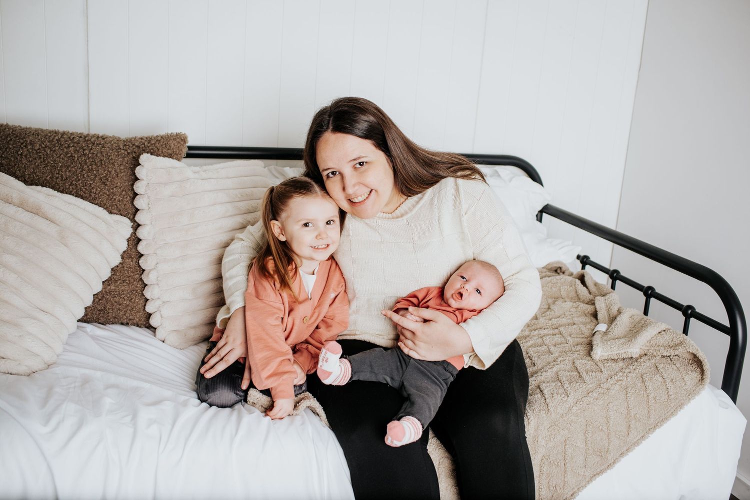 Candid black and white lifestyle photos of a family lounging on a bed during newborn photoshoot.