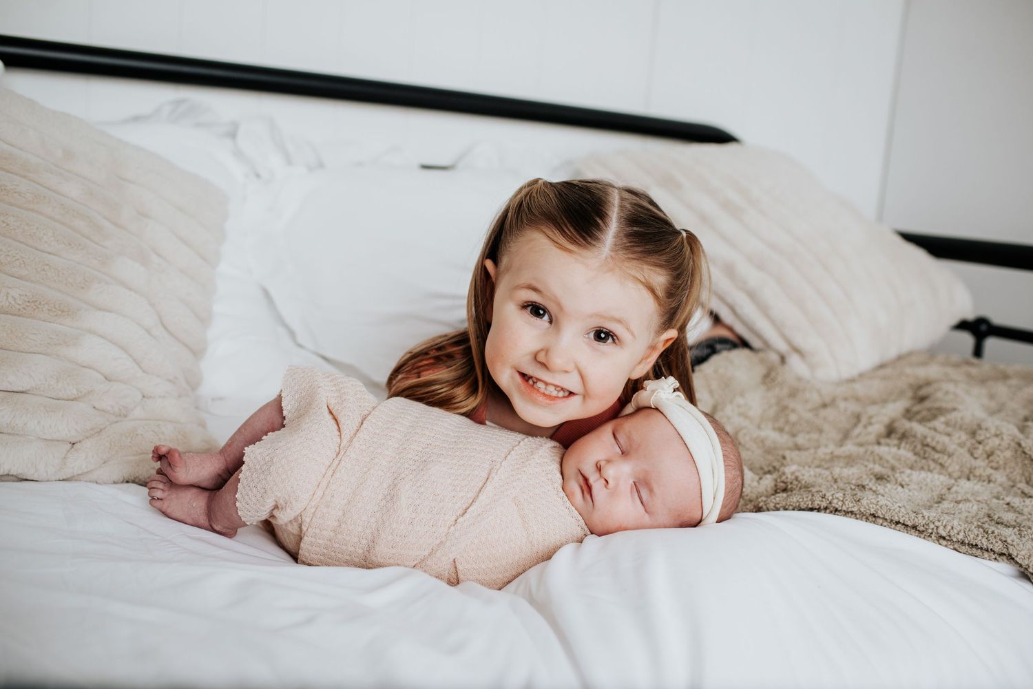 Sweet lifestyle photos of a family resting together on white bedding during newborn photoshoot.